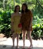 Emily and I, in yellow dresses and sandals waiting at the bus stop, there is green plants behind us and we are both smiling