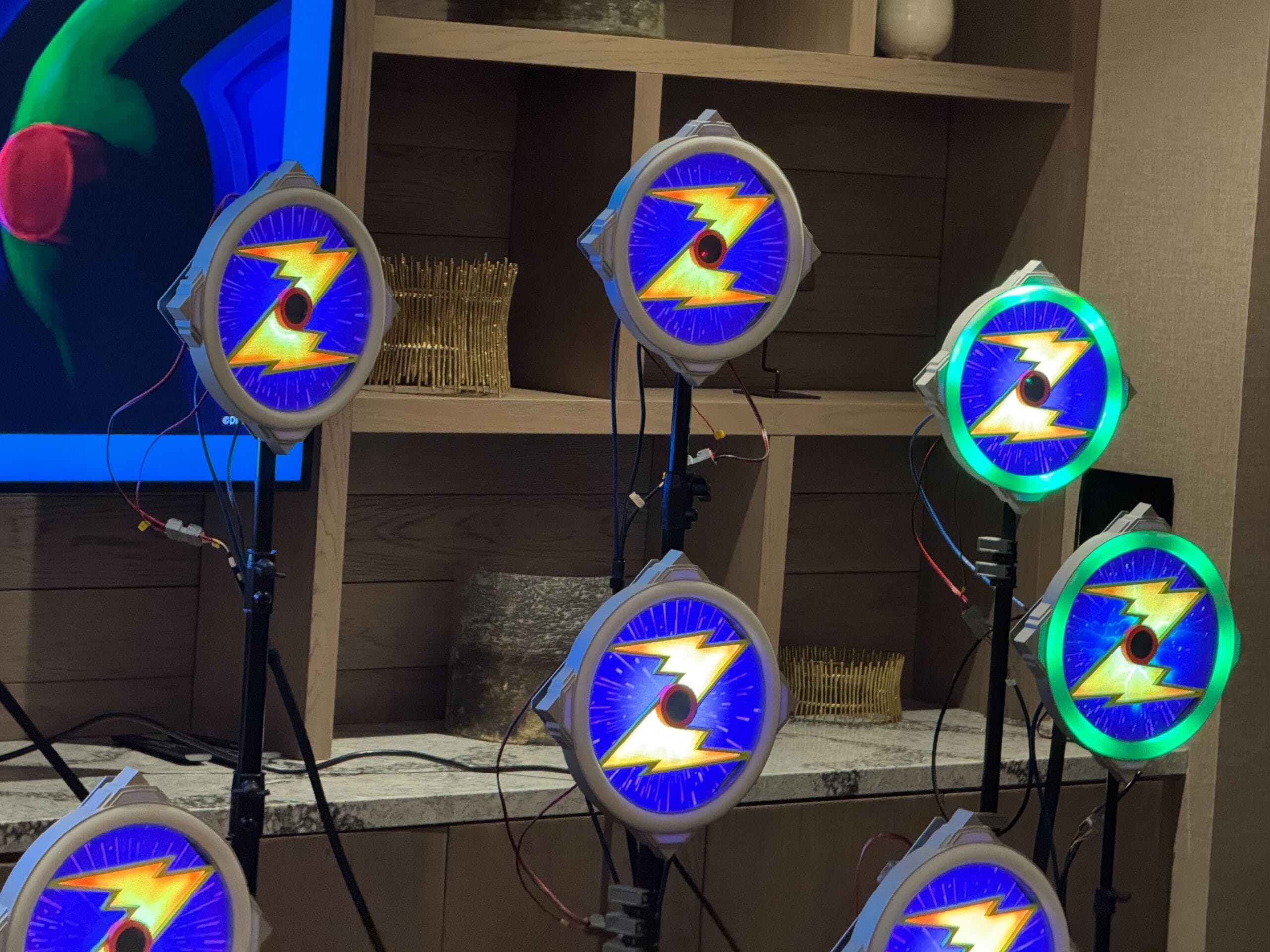 A set of illuminated circular displays with a yellow lightning bolt design on a blue background, mounted on stands and connected with wires.