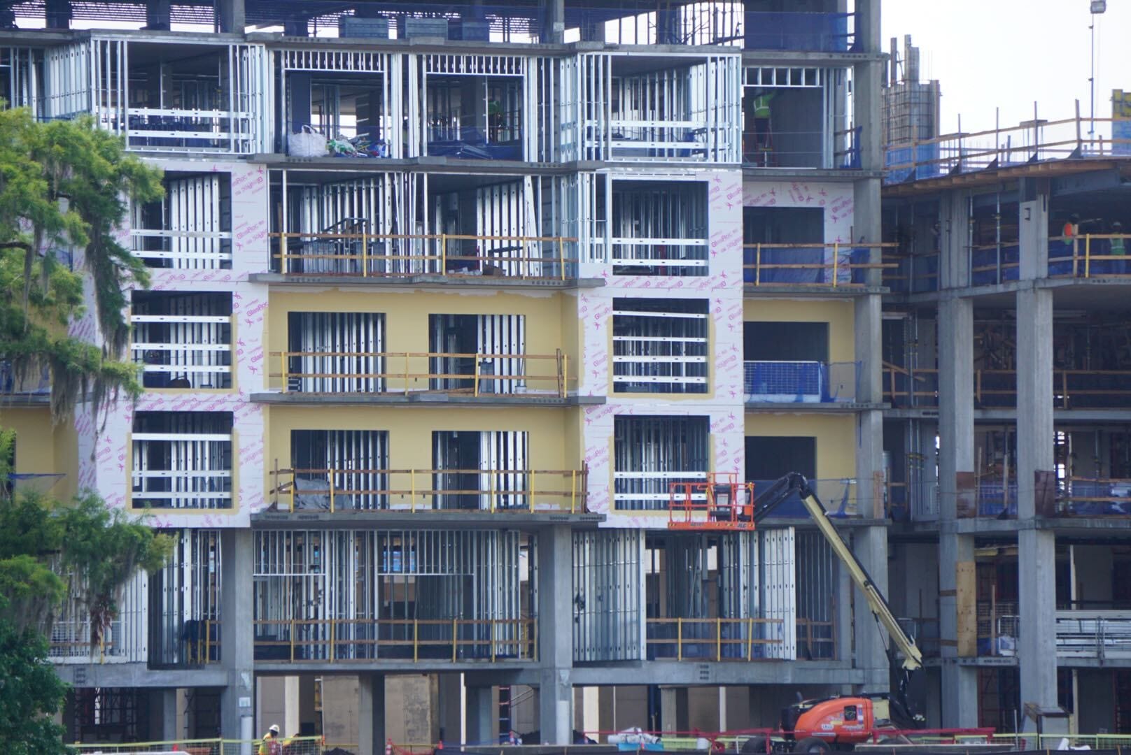 A multi-story building under construction with exposed steel framing and construction equipment in front.