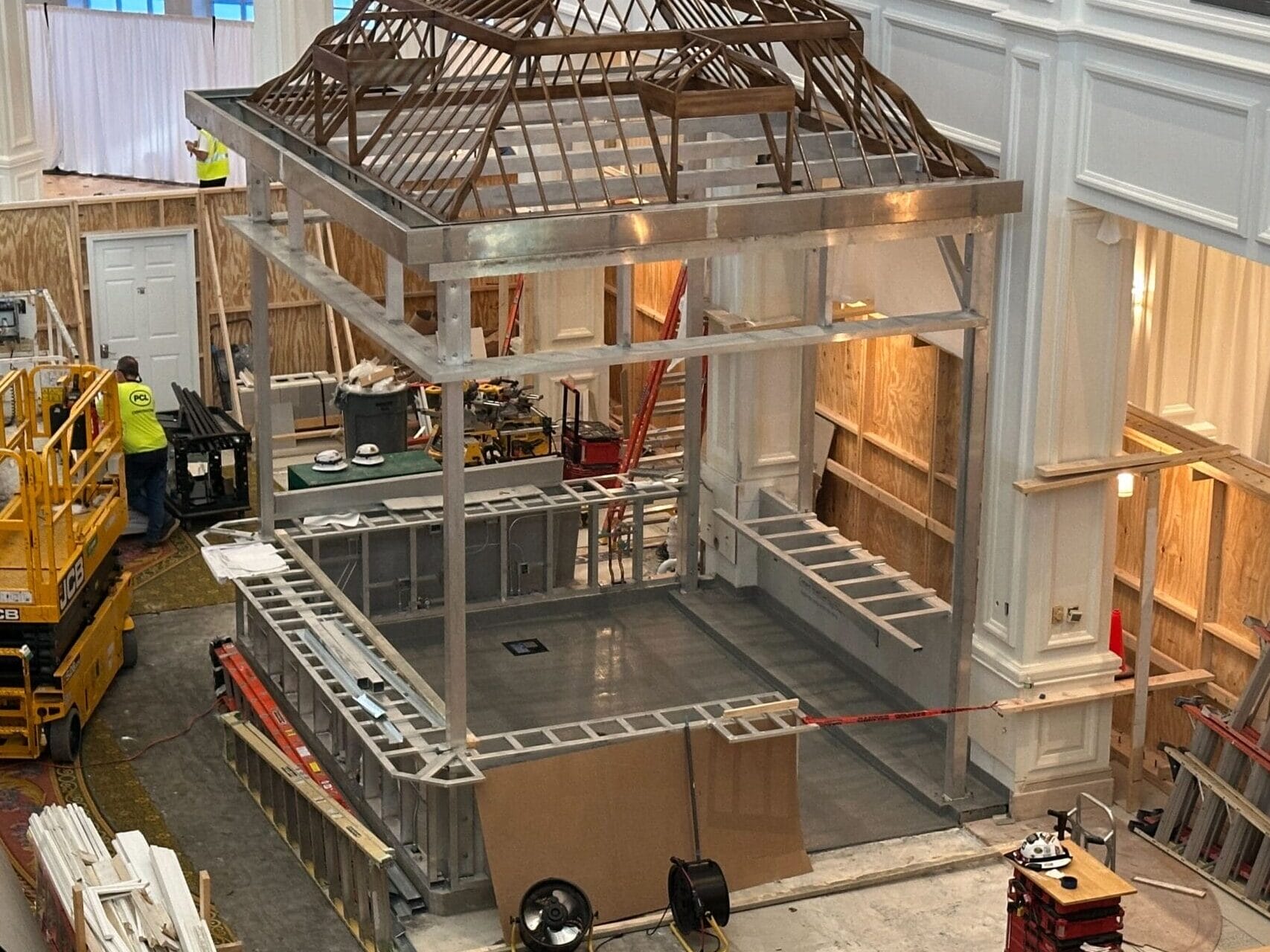 Construction site inside the Grand Floridian with framework for the Birdcage Bar and Tea Room Walls; workers using equipment.