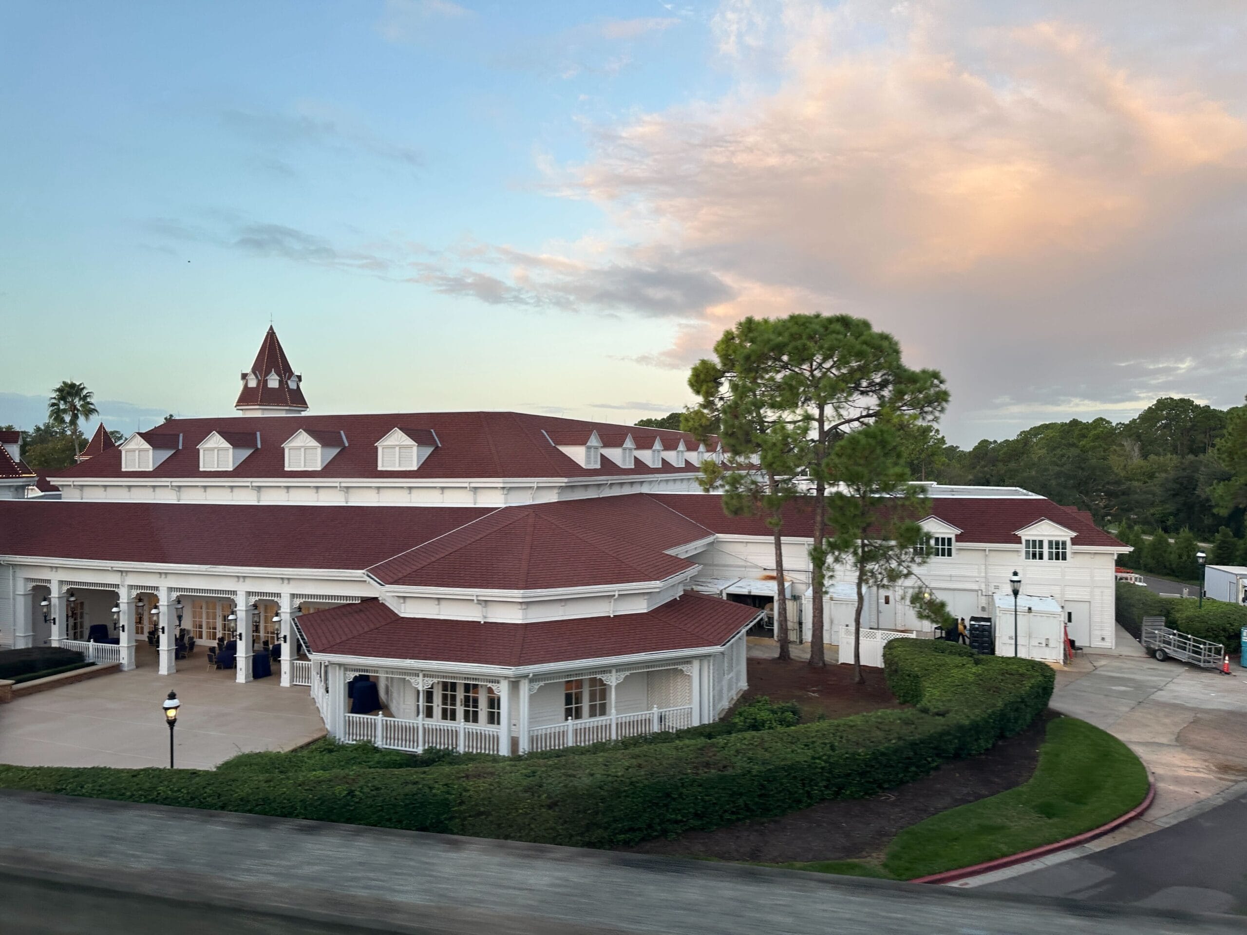 Victorian-style building with red roof and white trim at Disney's Grand Floridian Resort, glowing under sunset skies.