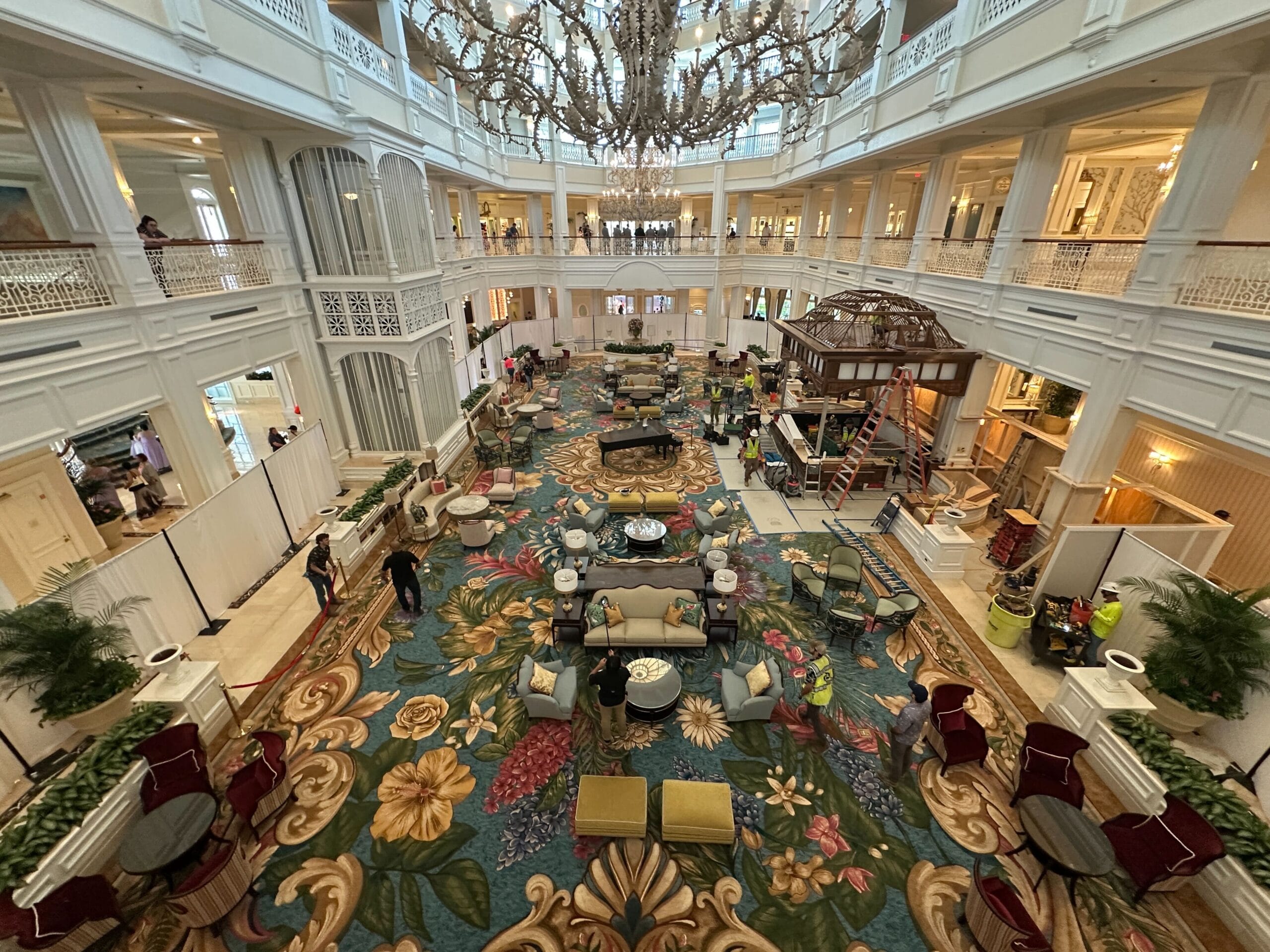 Grand Floridian Resort lobby with elegant furnishings, floral carpet, sparkling chandelier, and guests soaking in signature Disney luxury.