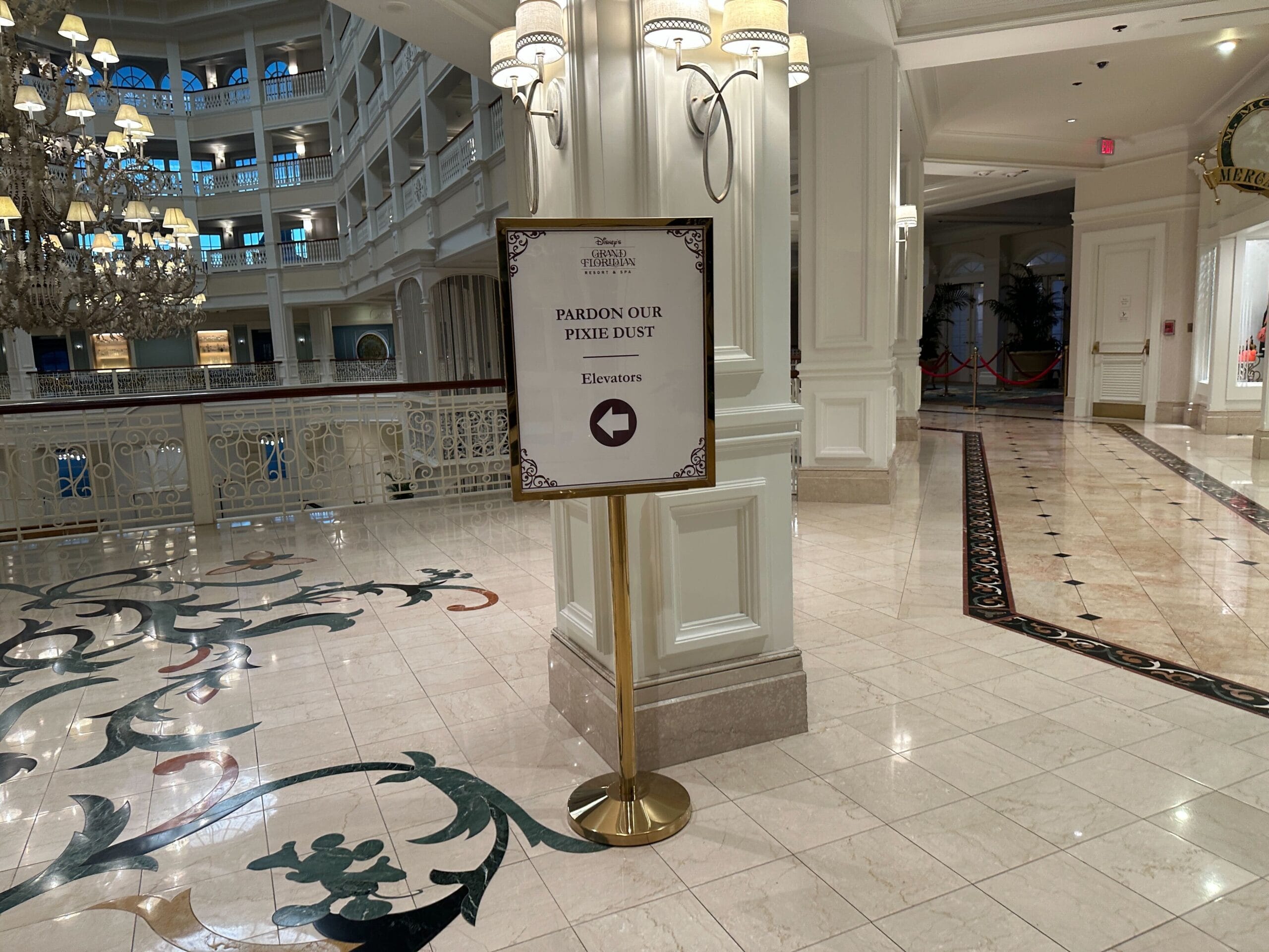 A sign in a hotel lobby reads Pardon Our Pixie Dust with an arrow pointing right toward the elevators.