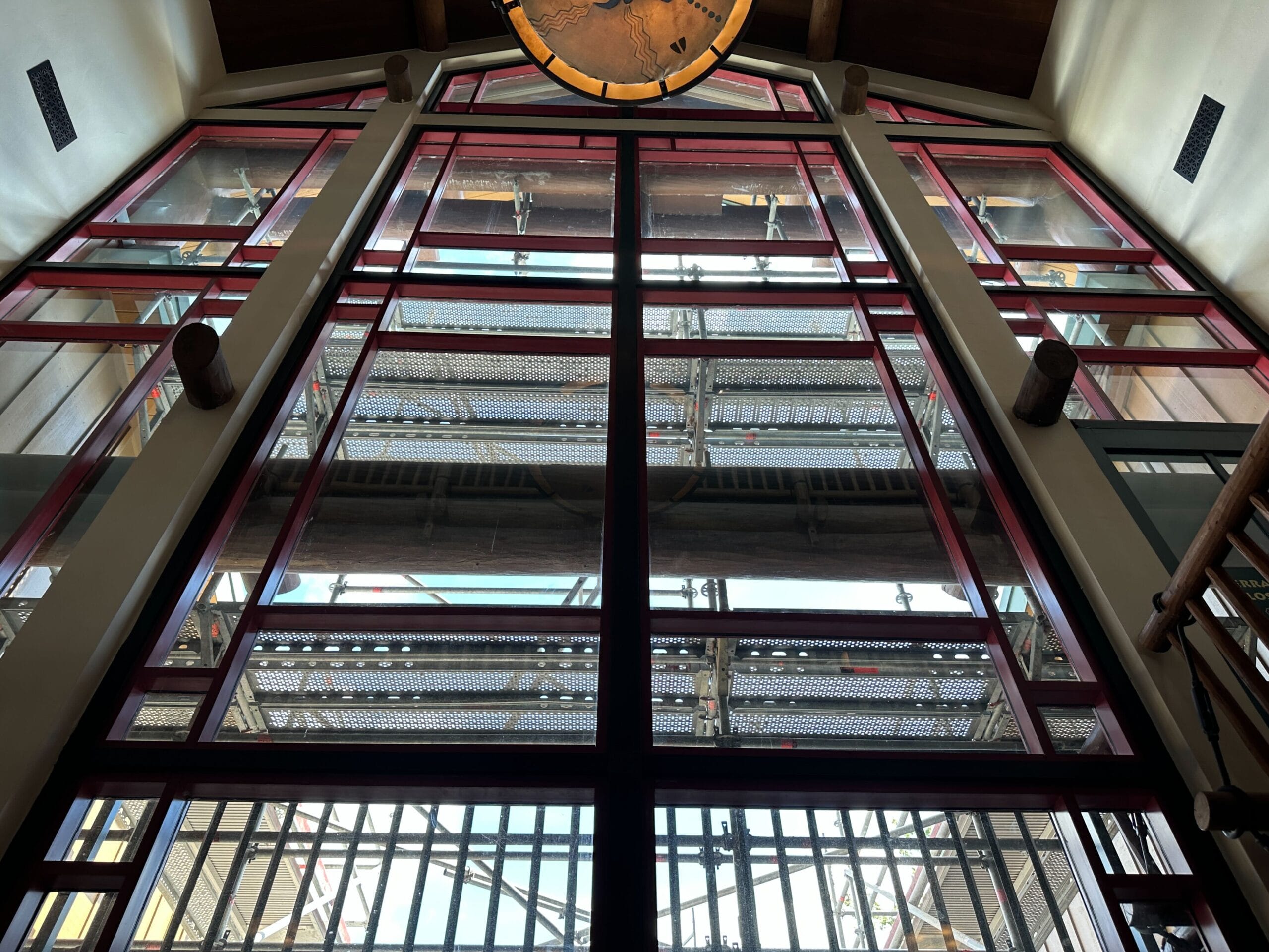 View looking up through large red-framed windows at ongoing Disney update outside Fort Wilderness Lodge, ceiling partly visible.