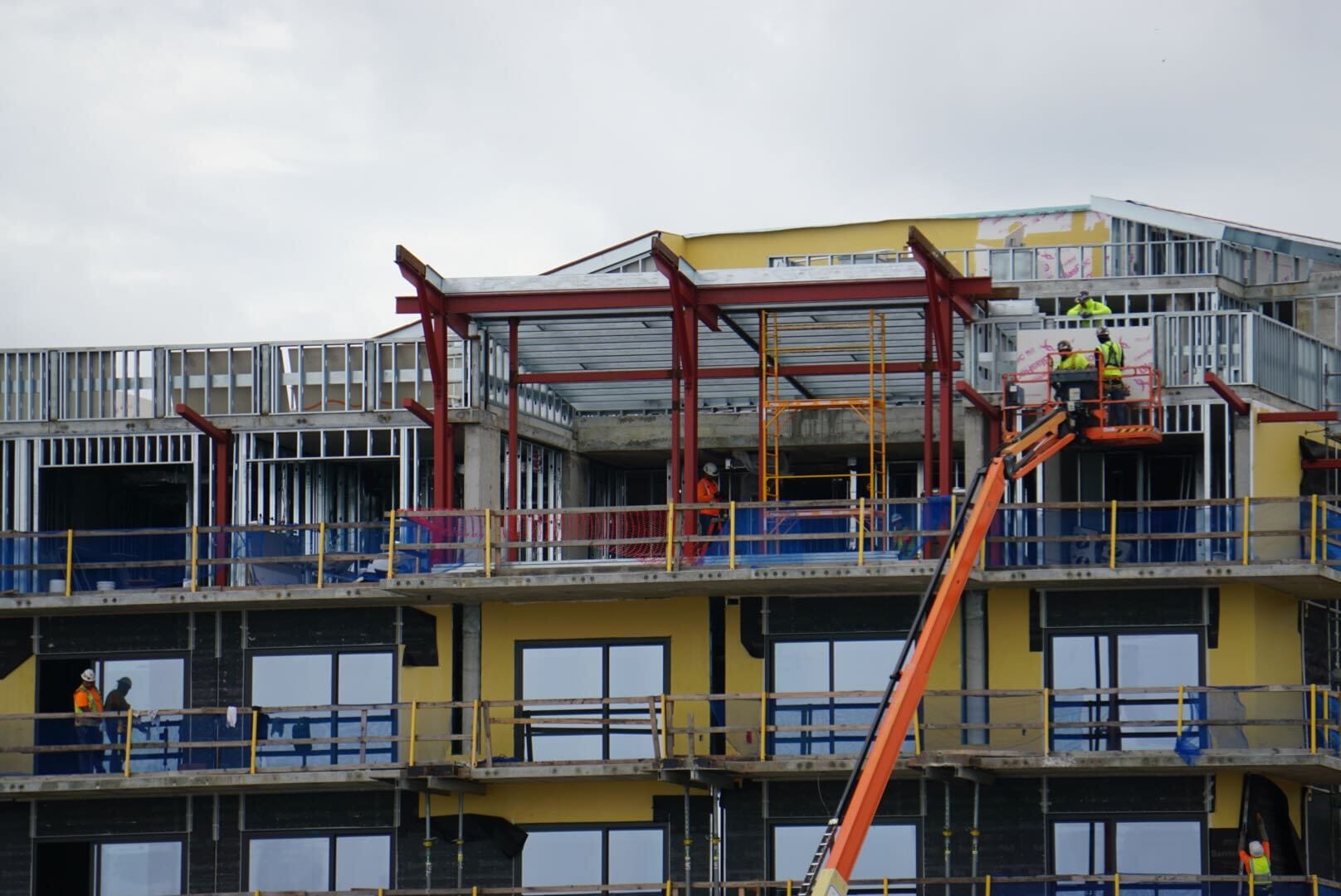 Construction workers on a lift assemble the steel frame for the new Lakeshore Update multi-story building.