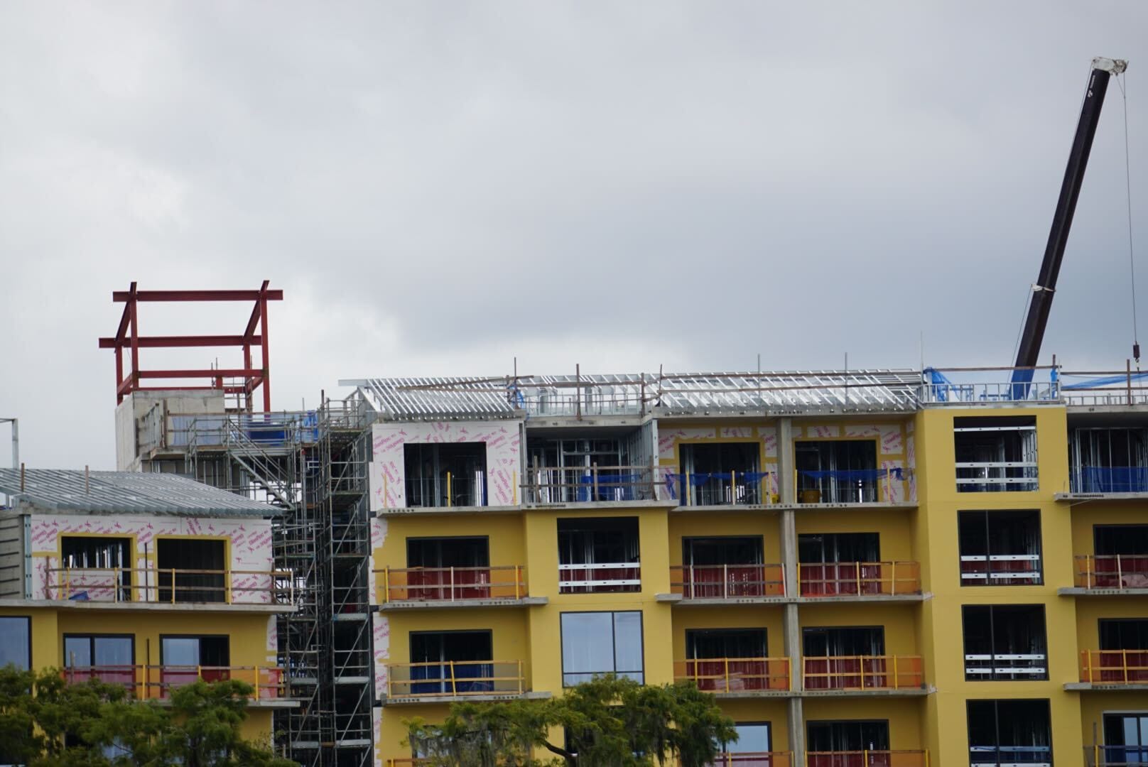 Lakeshore update: A yellow multi-story building under construction with scaffolding and a crane against a cloudy sky.