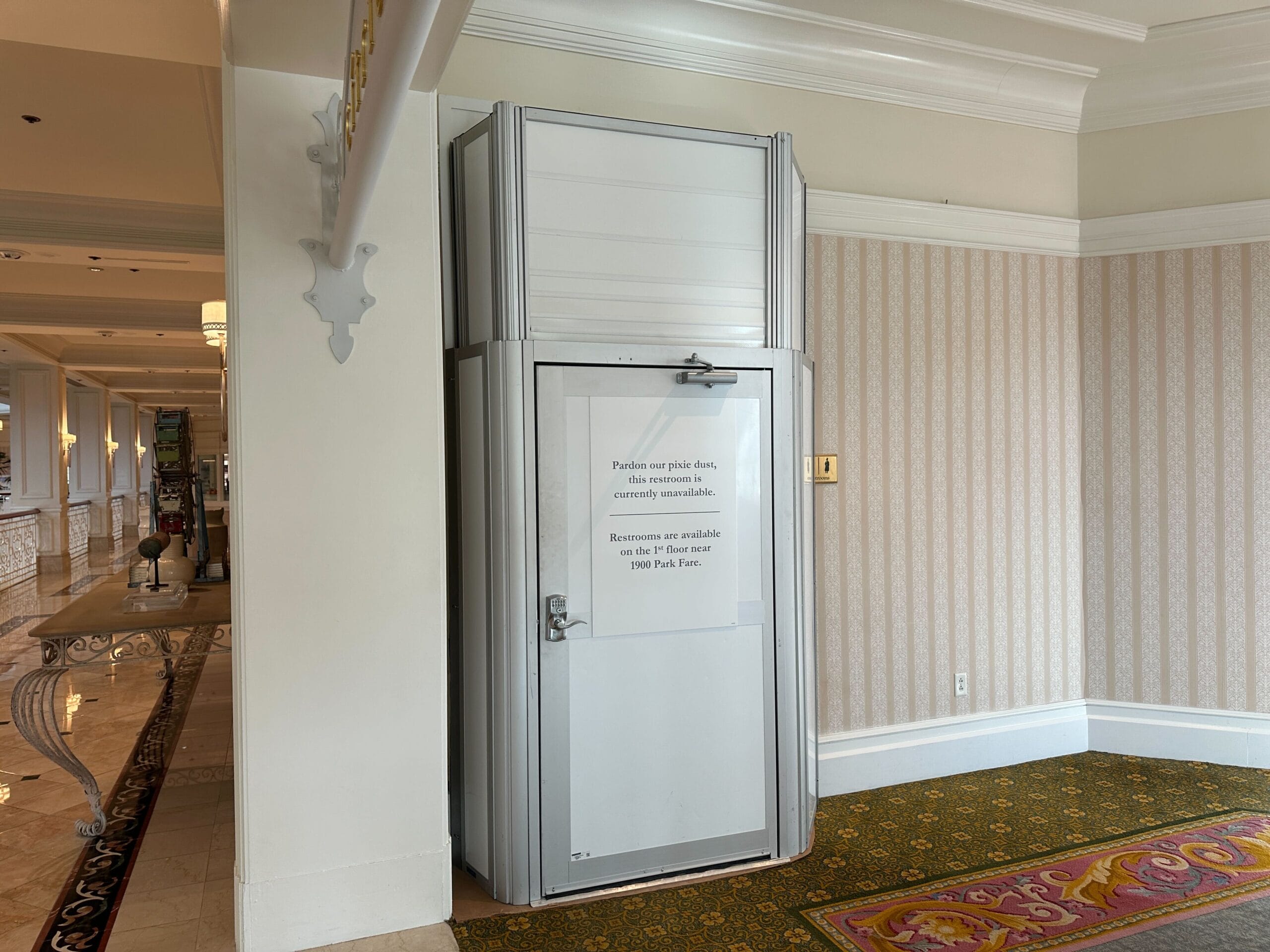 A small, closed elevator with a sign indicating it is currently unavailable, located in a carpeted hallway.