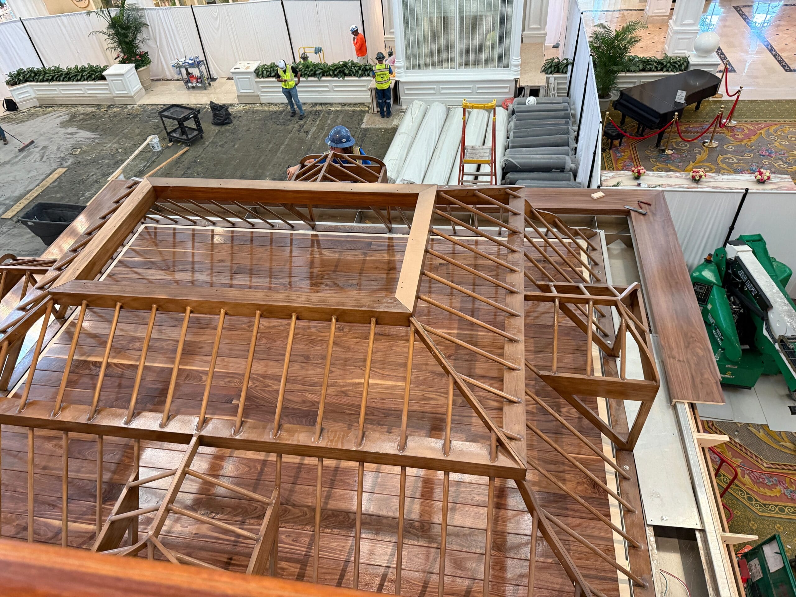 View from above of a wooden rooftop structure under construction, with workers and materials visible in the background.