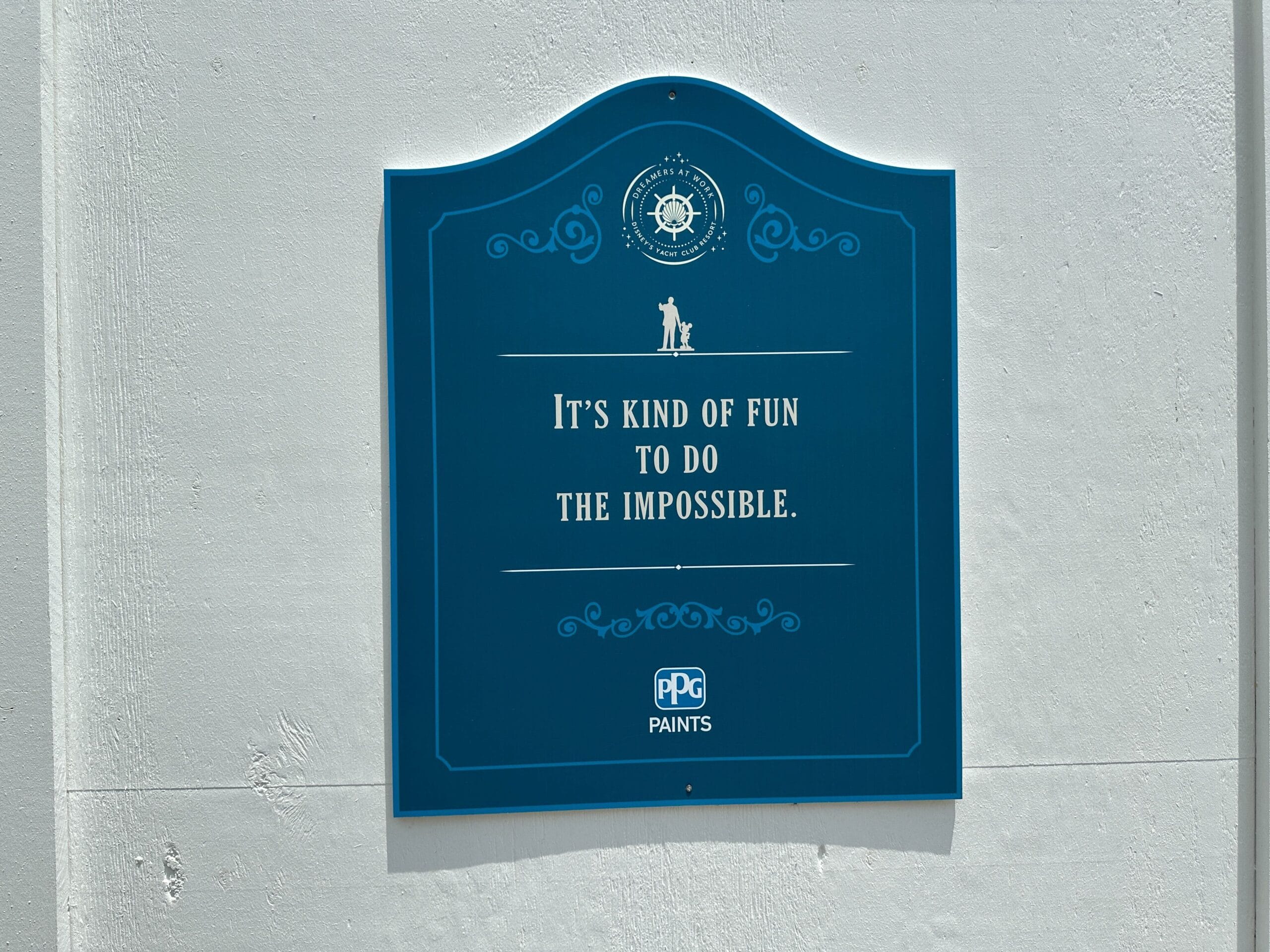 Blue plaque on a white wall reads: It’s kind of fun to do the impossible. PPG Paints logo at the bottom.