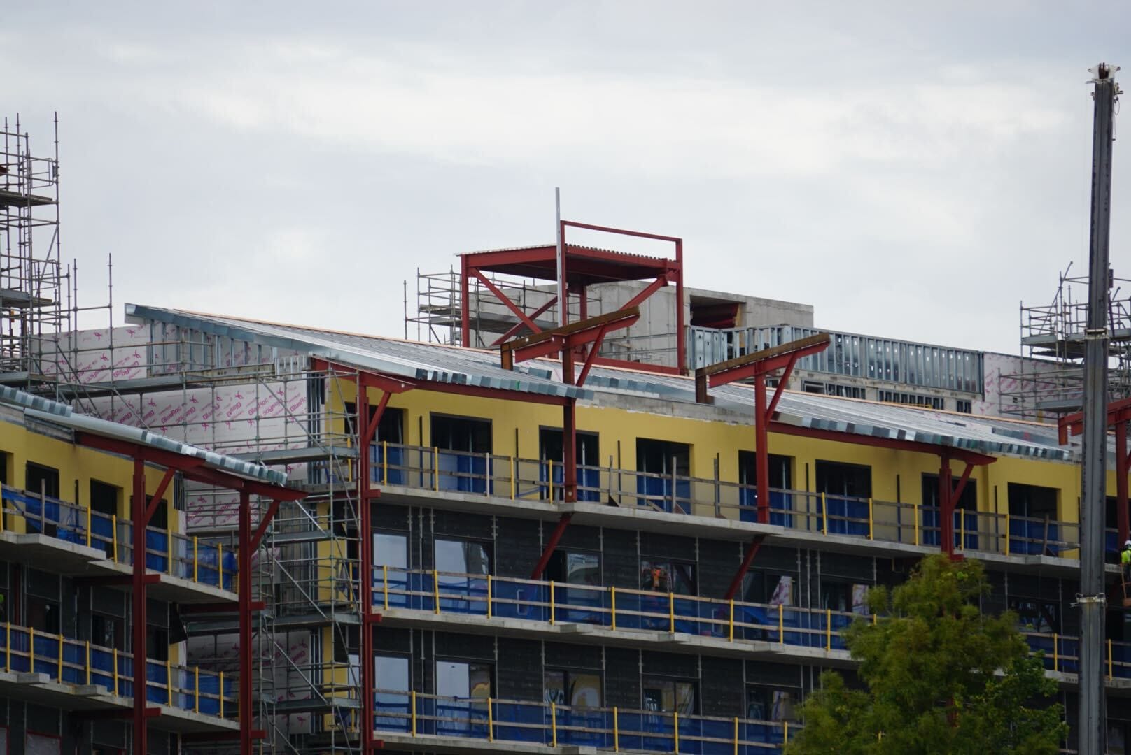 Lakeshore Update: Construction site of a multi-story building with scaffolding, yellow panels, and steel beams.