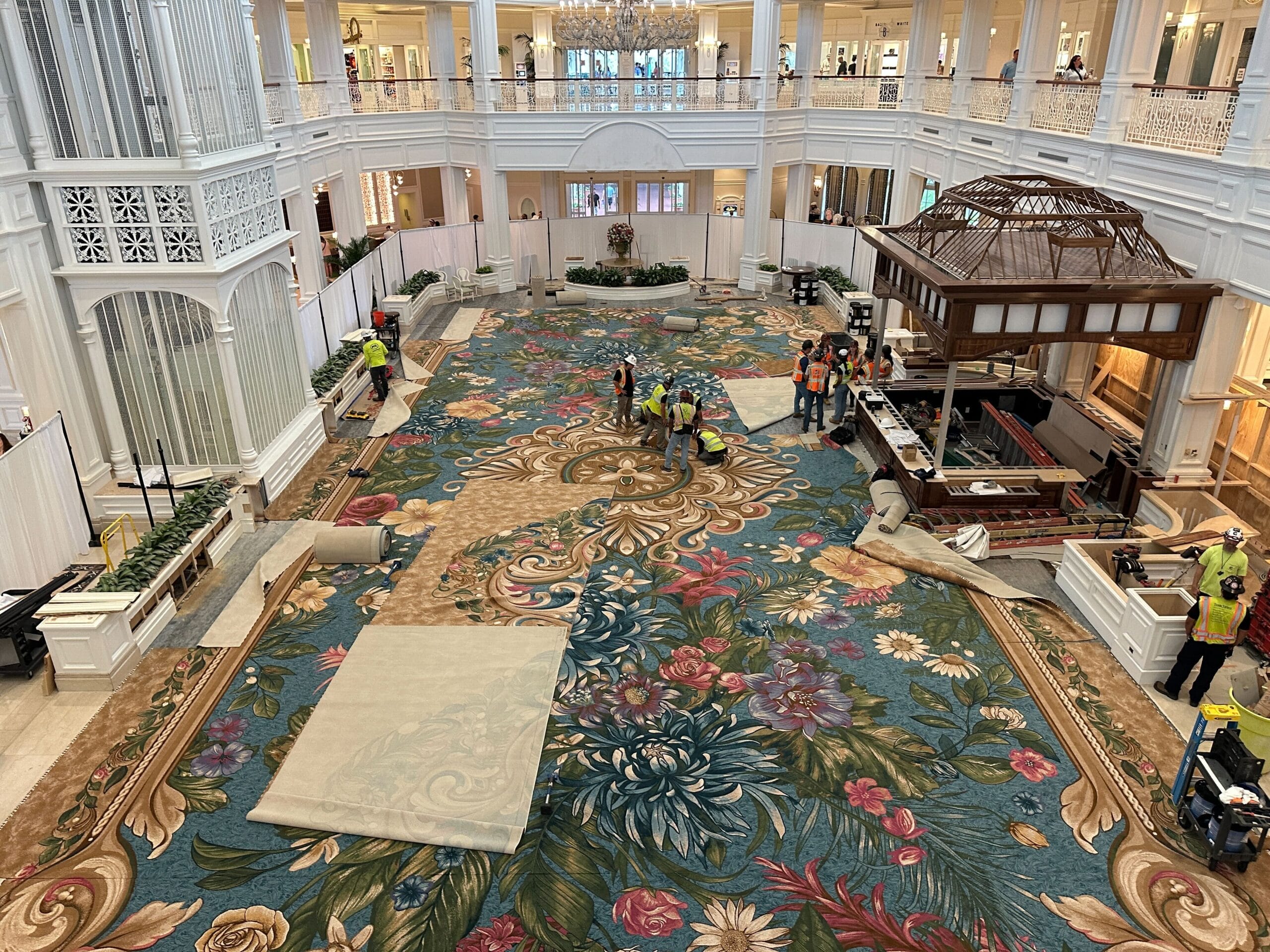 Workers in safety vests lay a fresh floral carpet in Grand Floridian’s airy, white lobby—no castle like those at Disney Parks here.