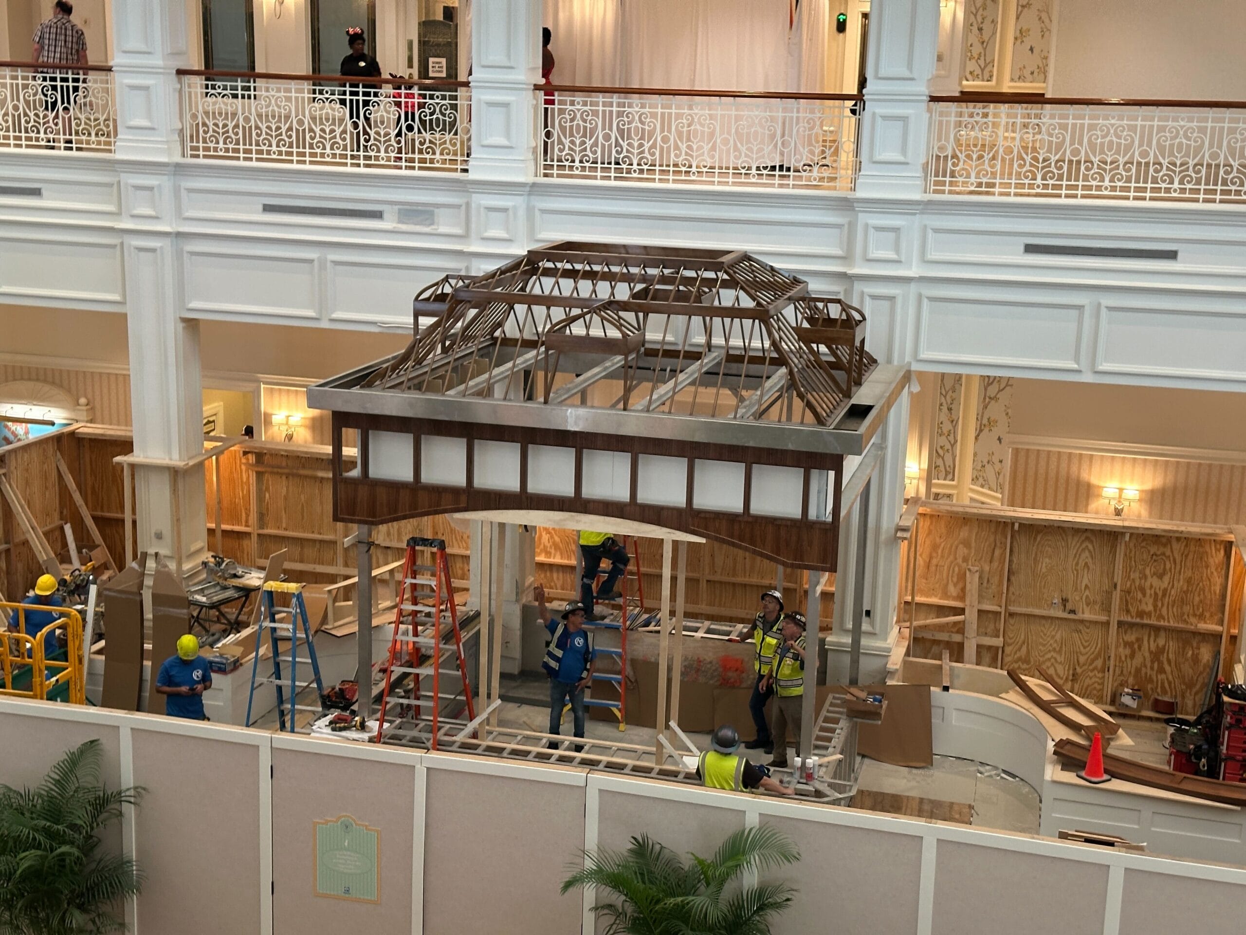 Workers in hard hats construct a wooden pavilion inside the Disney lobby of the Grand Floridian Resort’s ornate atrium.