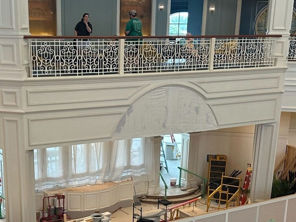 Hotel lobby with construction barriers, people sitting on sofas, and others walking on the upper level.