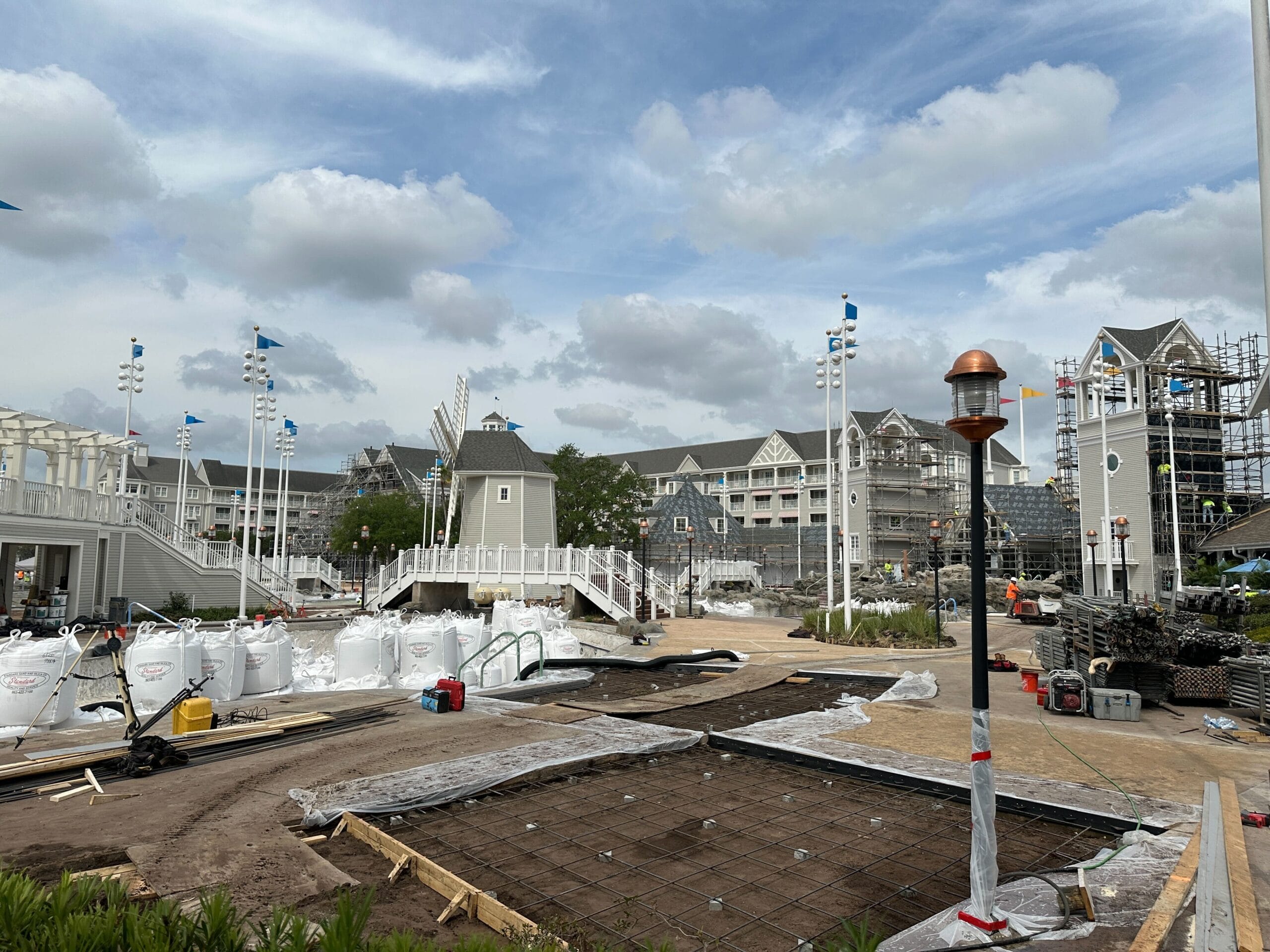 Hotel grounds under construction with scaffolding, building materials, and cloudy sky in the background.