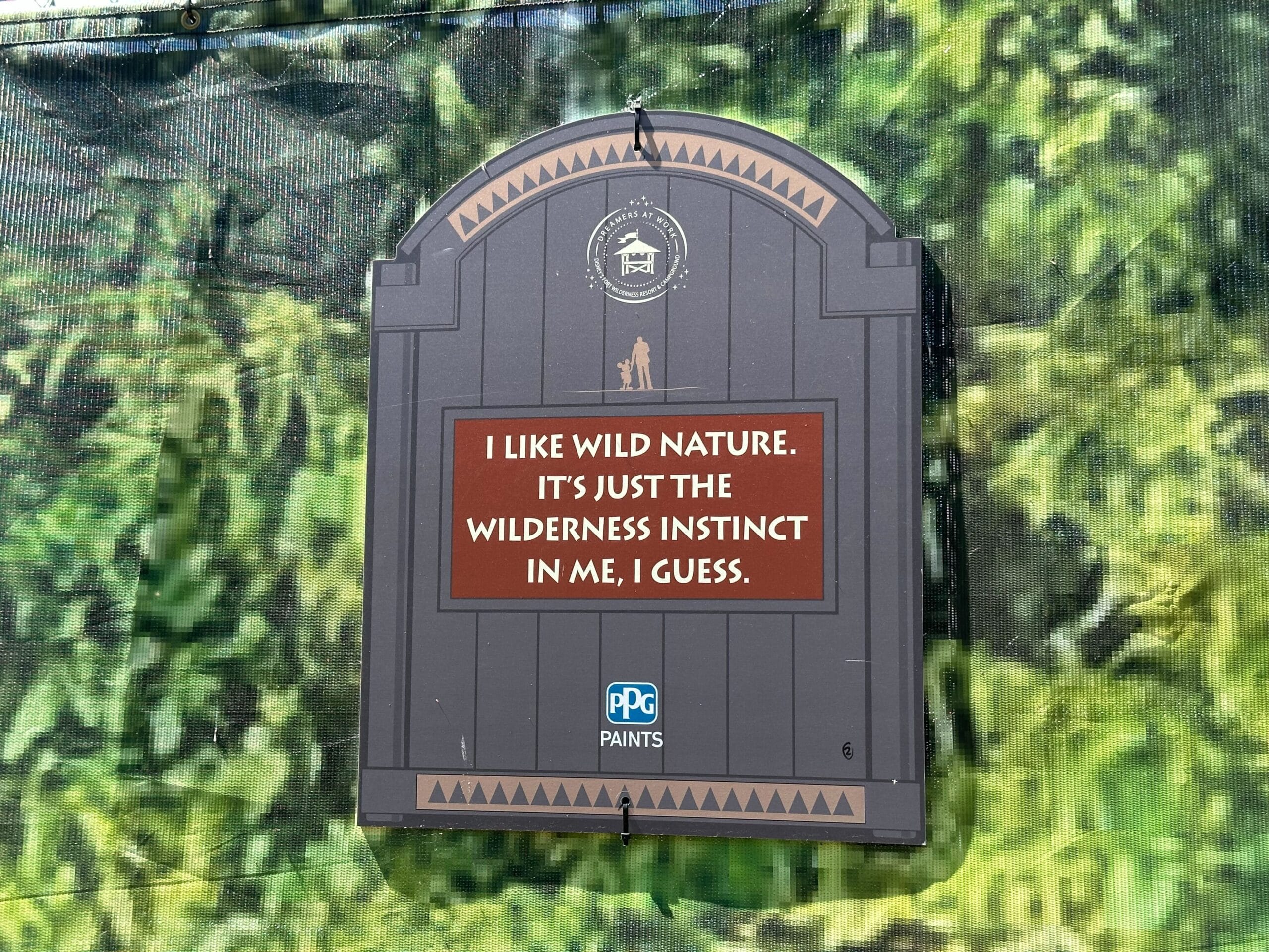A sign set against a green leafy backdrop reads, I like wild nature. It's just the wilderness instinct in me, I guess, with a PPG Paints logo at the bottom.