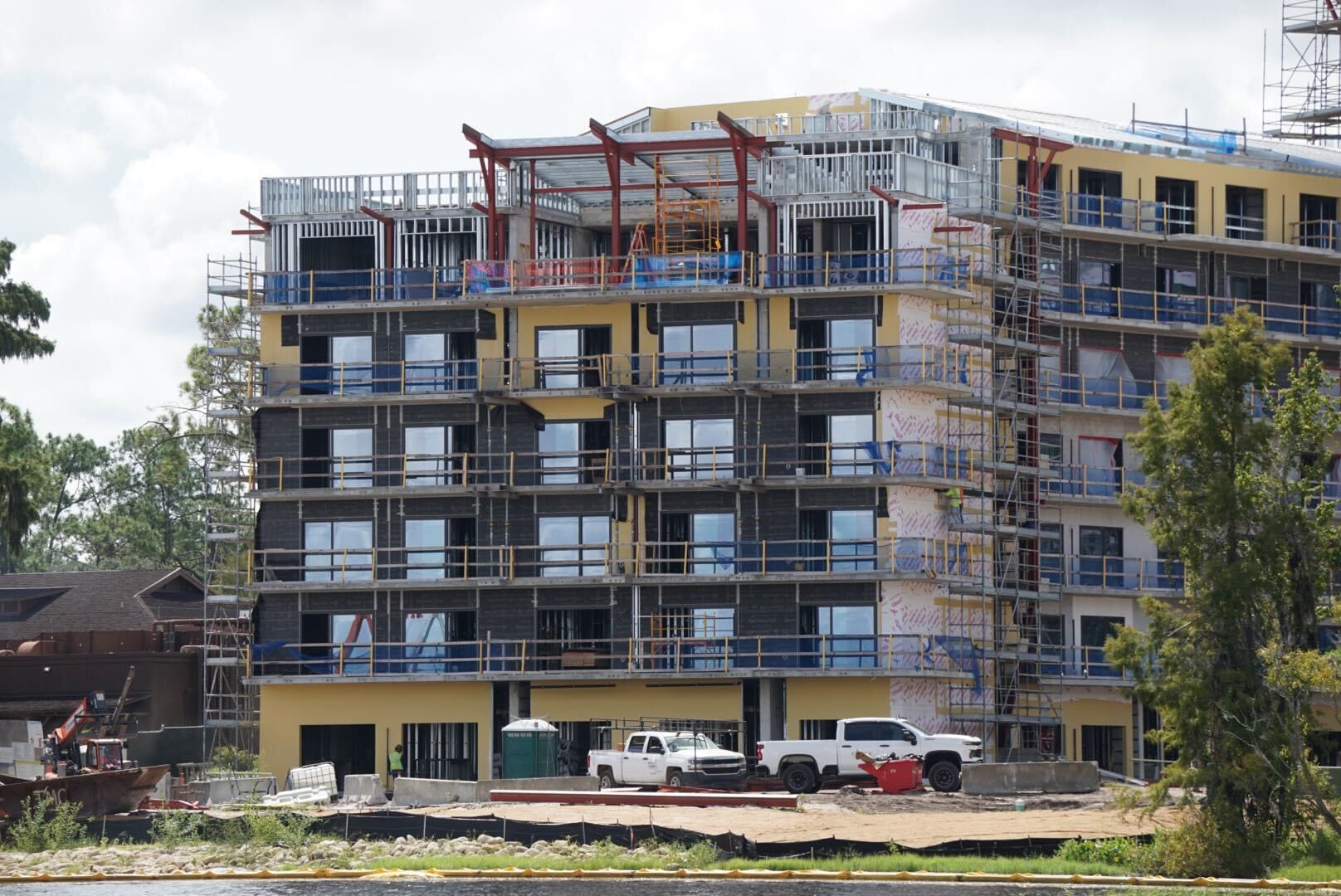 A multi-story building under construction with scaffolding, trucks, and construction equipment in front.