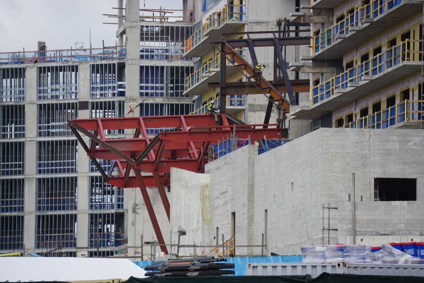 Construction Updates: Construction site with steel beams, concrete walls, scaffolding, and workers near Lakeshore Lodge high-rises.