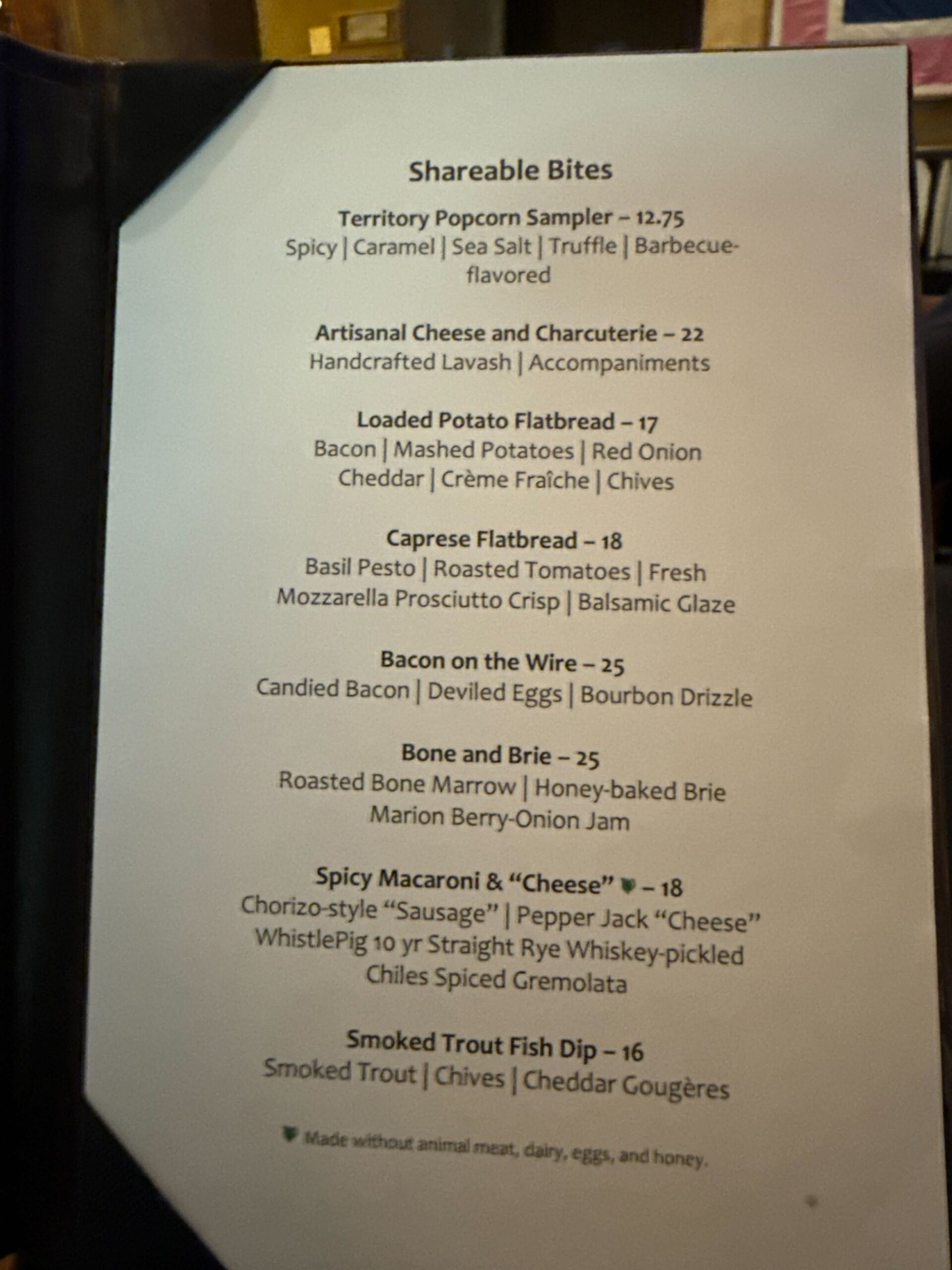 Menu titled Shareable Bites listing items such as popcorn sampler, artisanal cheese, loaded potato flatbread, caprese flatbread, bacon on the wire, boozy mac and cheese, and smoked trout fish dip.