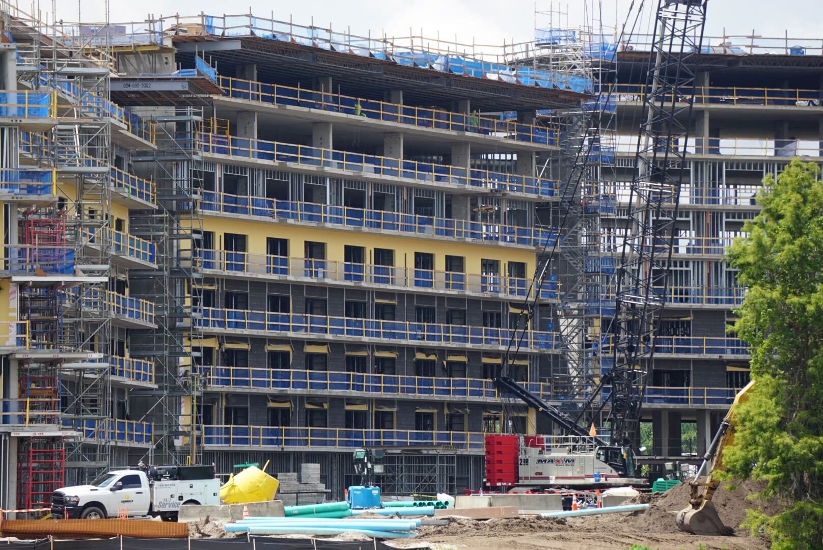 Lakeshore Lodge Construction: A multi-story building rising, with scaffolding, cranes, and construction vehicles on site.