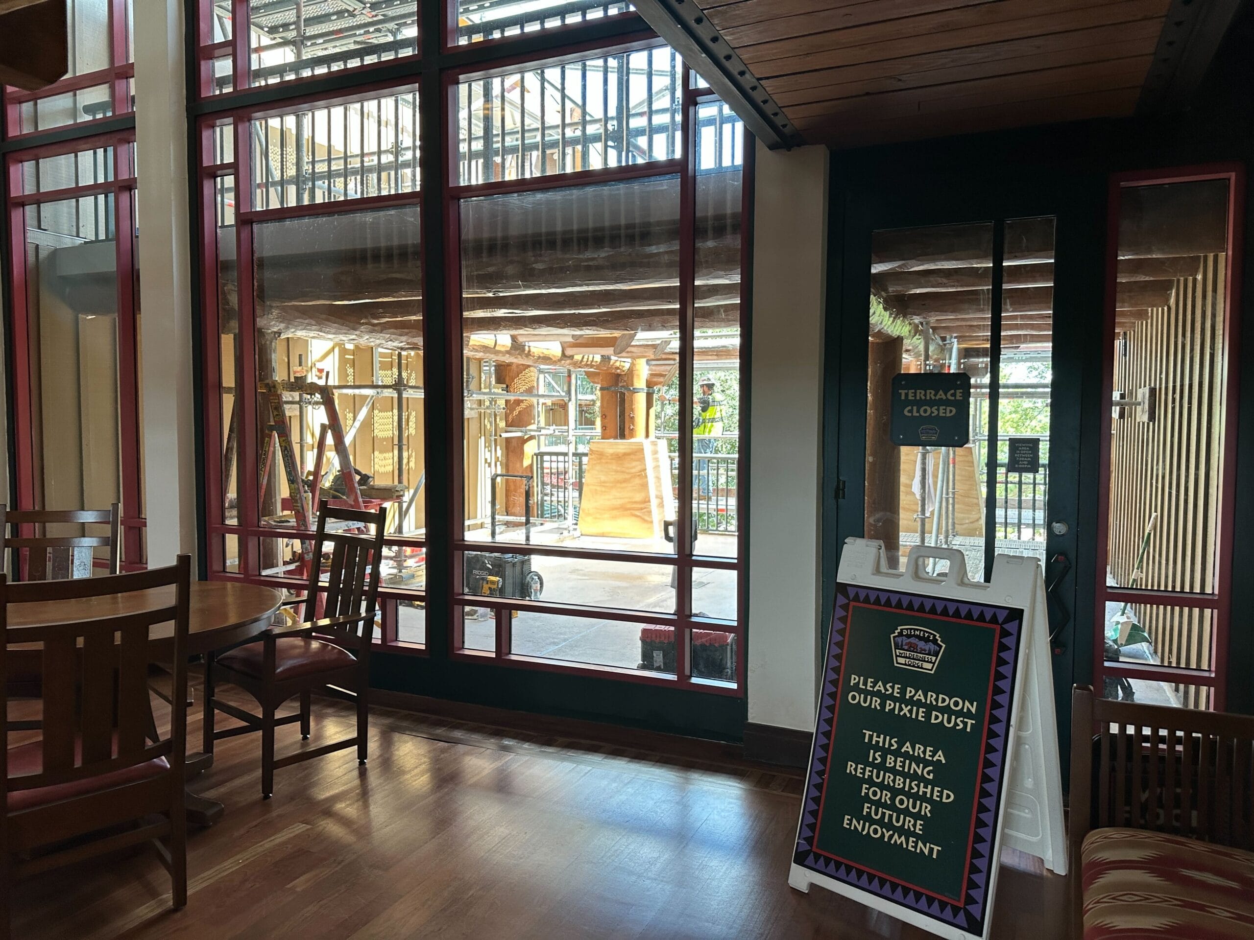 Sunlit indoor seating at Fort Wilderness Lodge; outdoor terrace closed for update, sign explains ongoing work.
