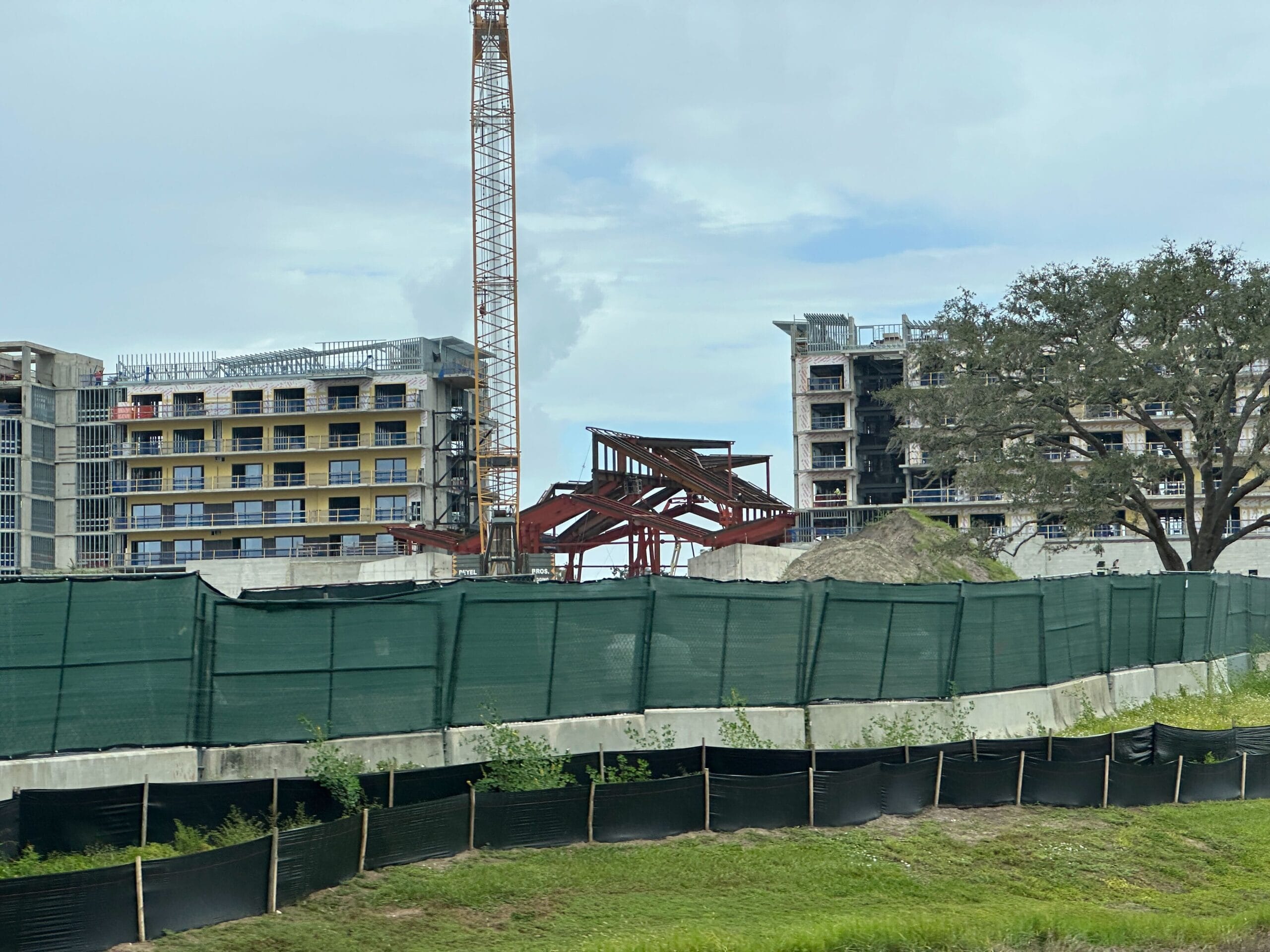Construction Updates: A construction site with two buildings, crane, steel framework, and green fencing at Lakeshore Lodge.