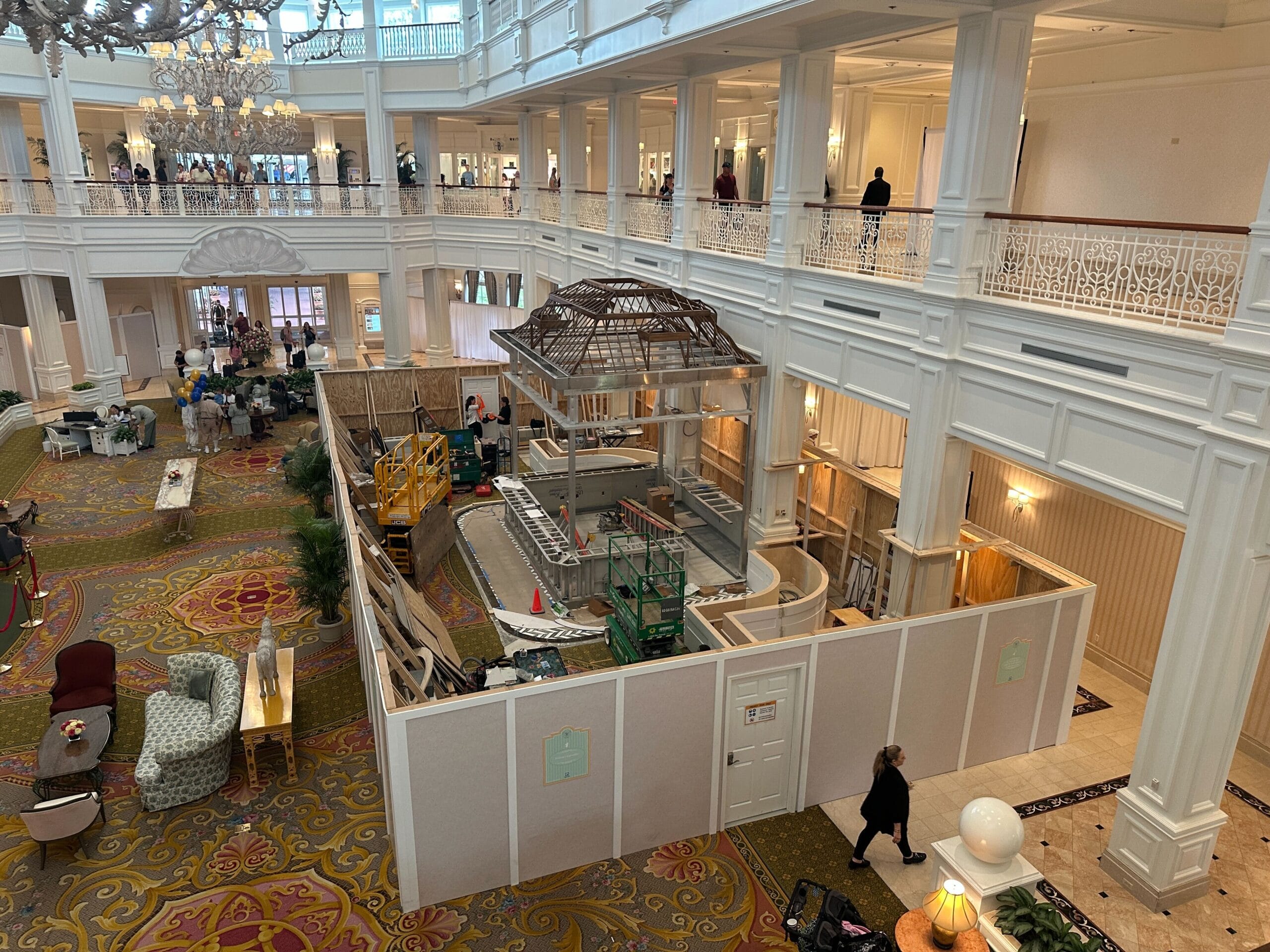 A hotel lobby with a large area under construction, surrounded by white barriers and scaffolding.