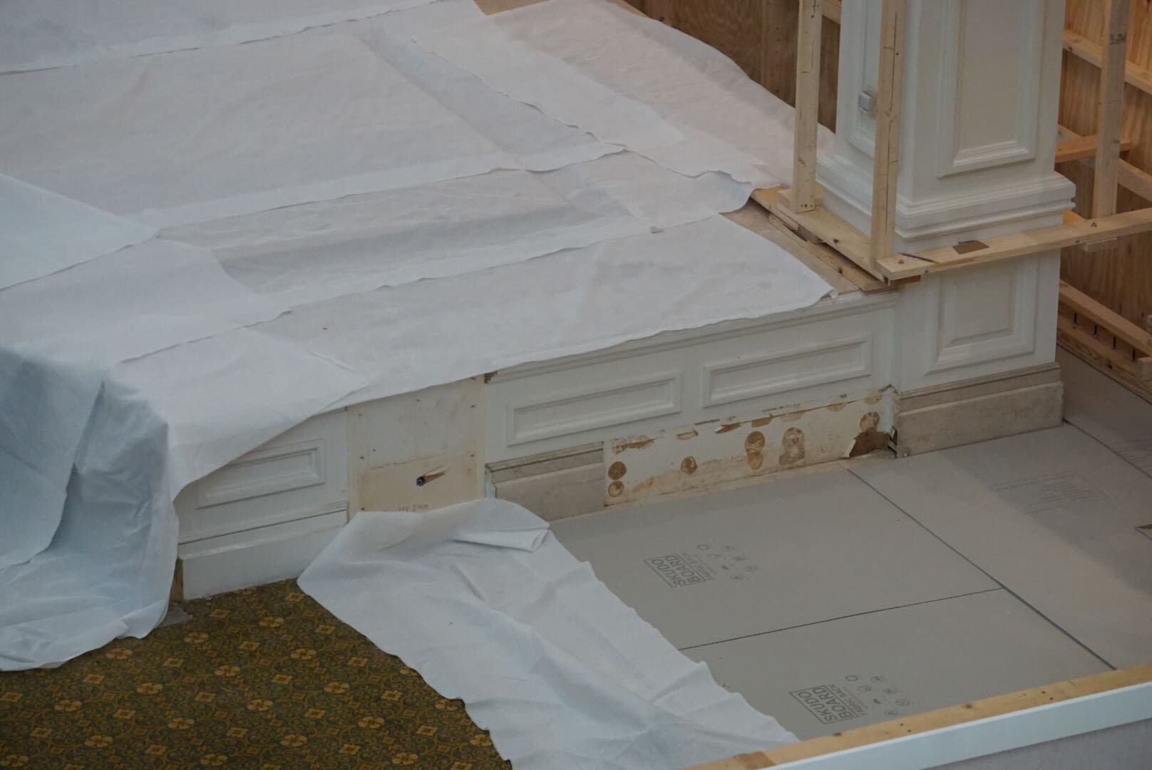 White sheets cover a partially renovated area with exposed wood, hinting at H2O Glow After Hours food prep nearby.