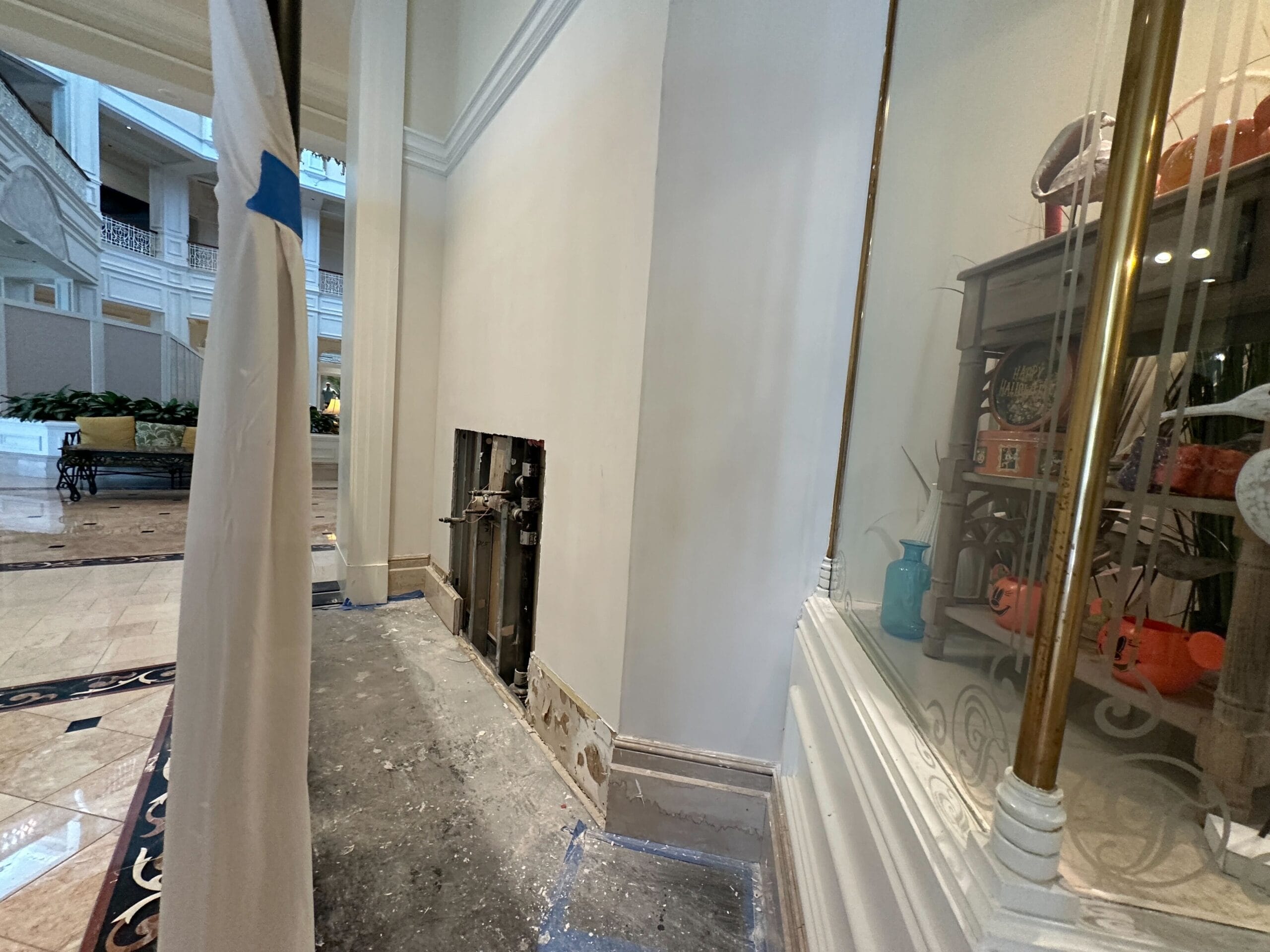 A hotel hallway under repair at Disney's Grand Floridian Resort with an open wall panel and tile flooring.