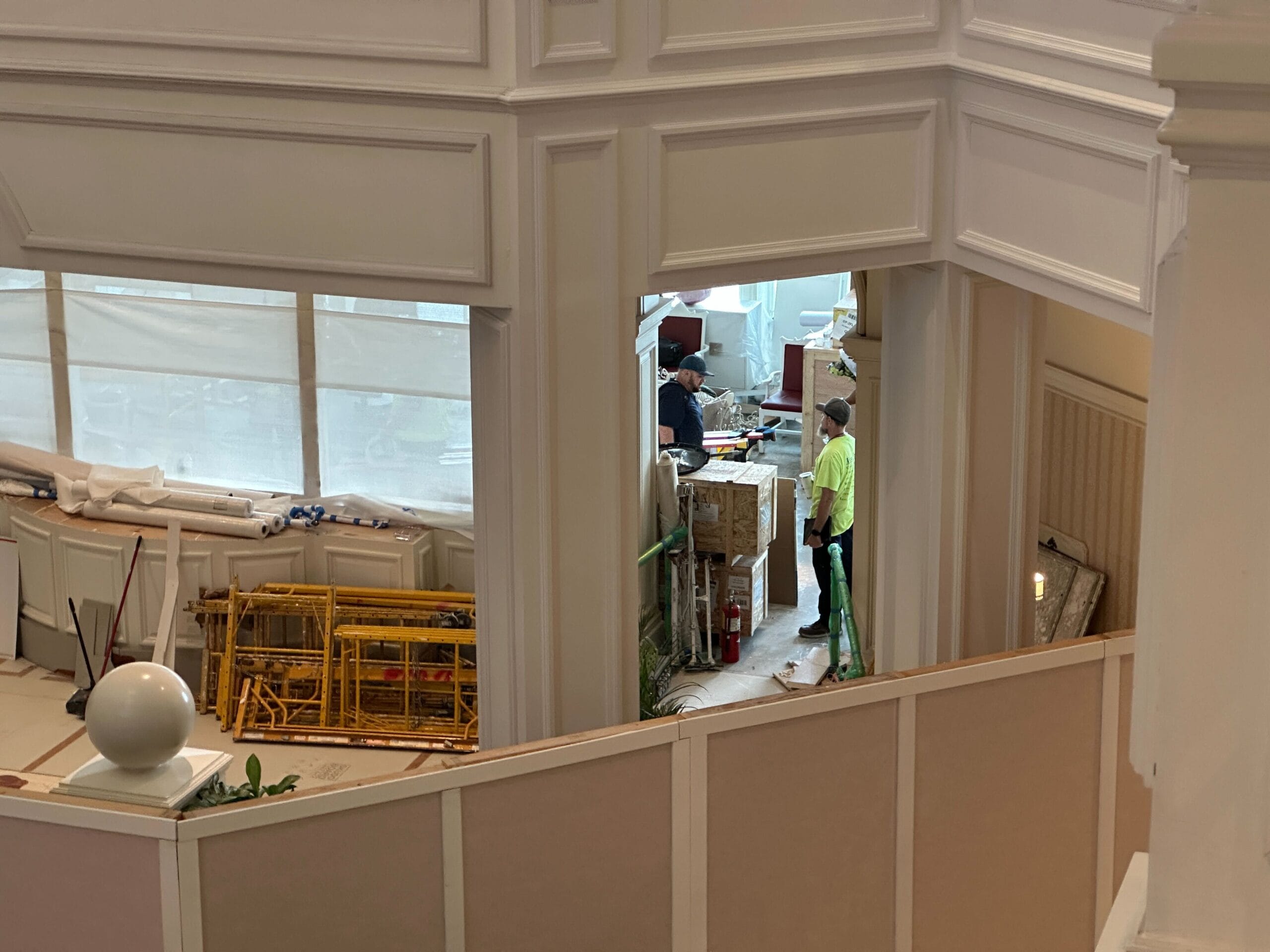 Two workers stand in a partially renovated Grand Floridian Tea Room, surrounded by construction materials and equipment.