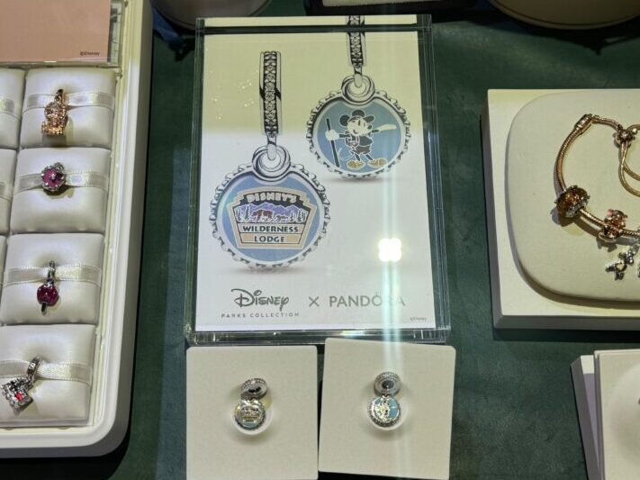 Display of Disney-themed Pandora jewelry, including various charms, bracelets, and earrings. The sign indicates a purchase limit of two items per guest. Highlighting the intricate details, each Pandora charm captures the magic of Disney in exquisite fashion.
