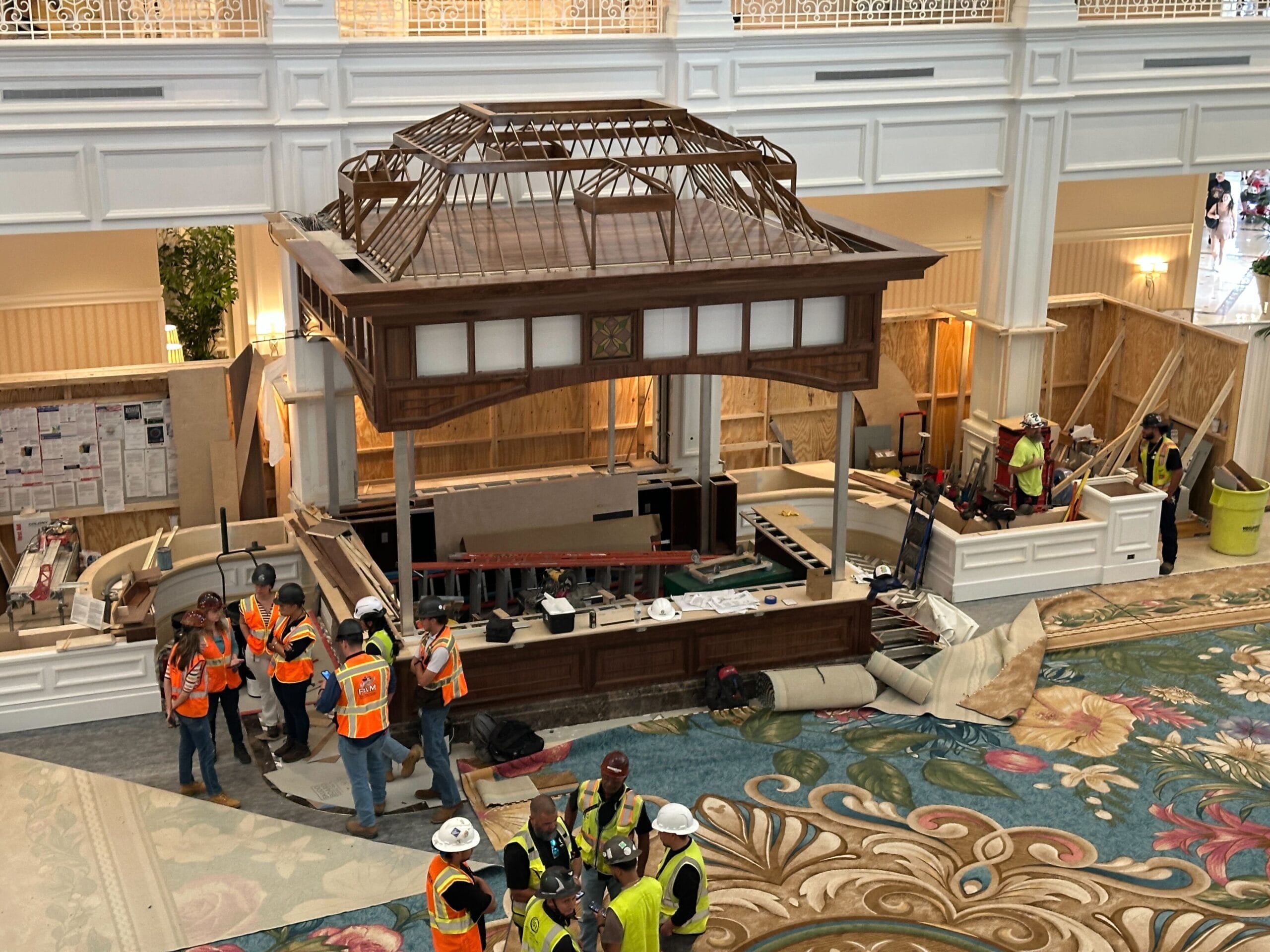 Workers in safety gear prep a wooden structure as painting starts in the Grand Floridian, echoing the resort’s elegant Disney style.