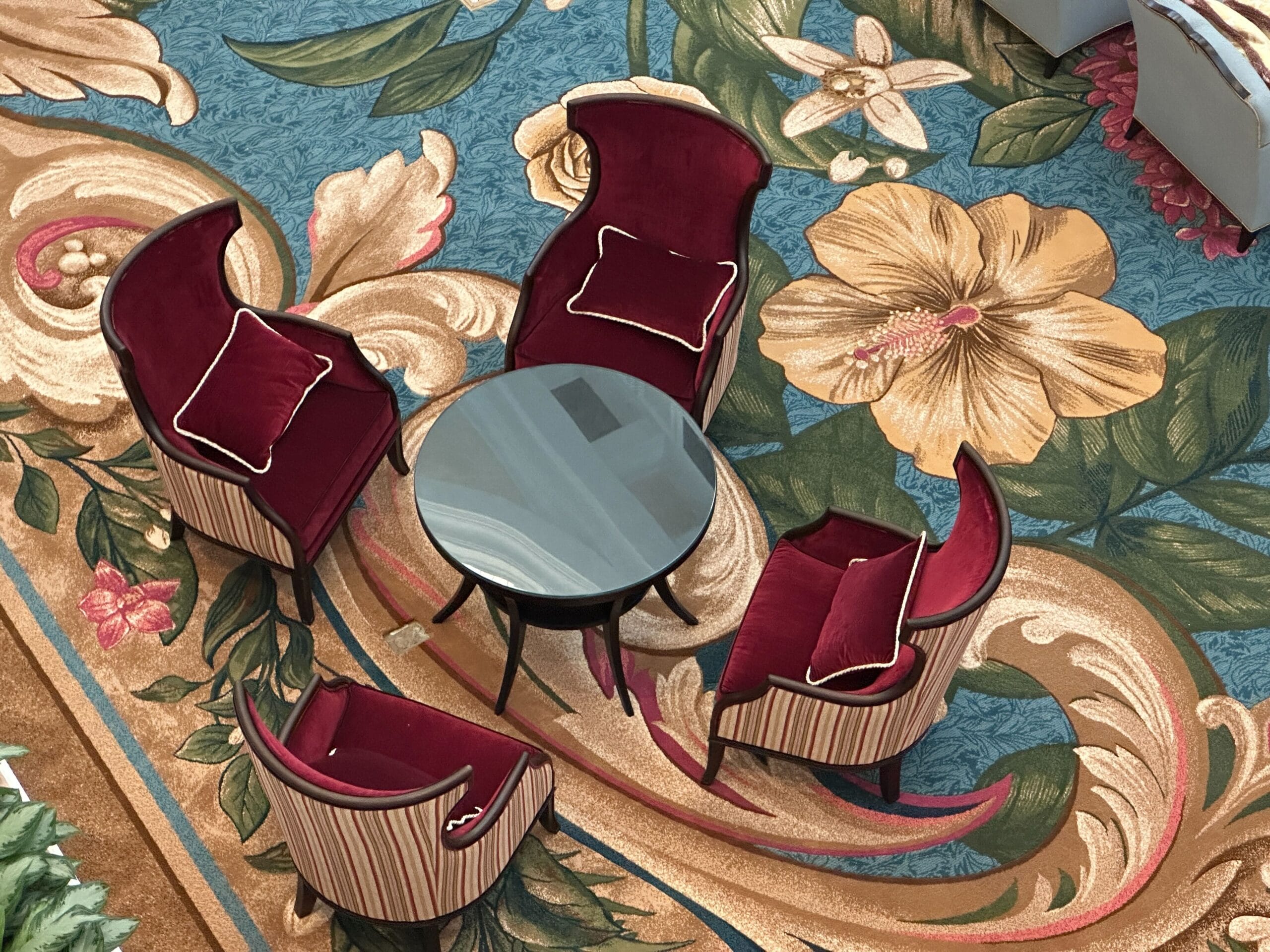 Four red velvet chairs circle a round table atop a floral carpet in Disney’s Grand Floridian Resort lobby, no castle visible here.