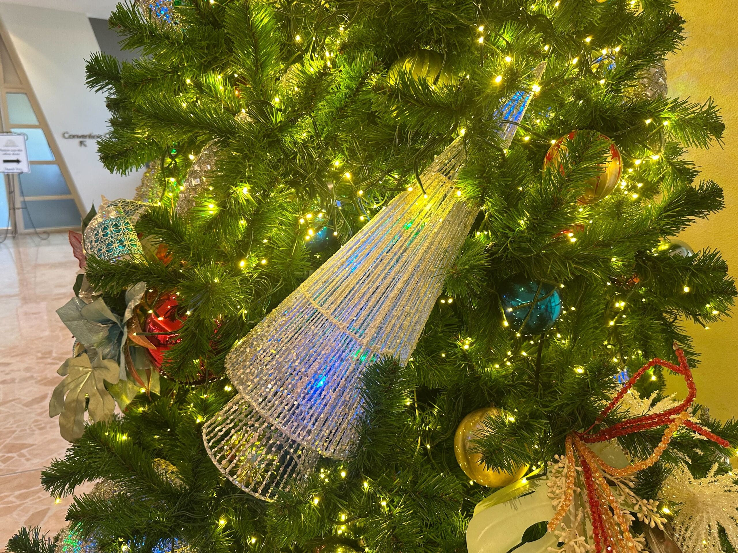 A decorated Christmas tree with lights, a silver cone ornament, and various baubles.