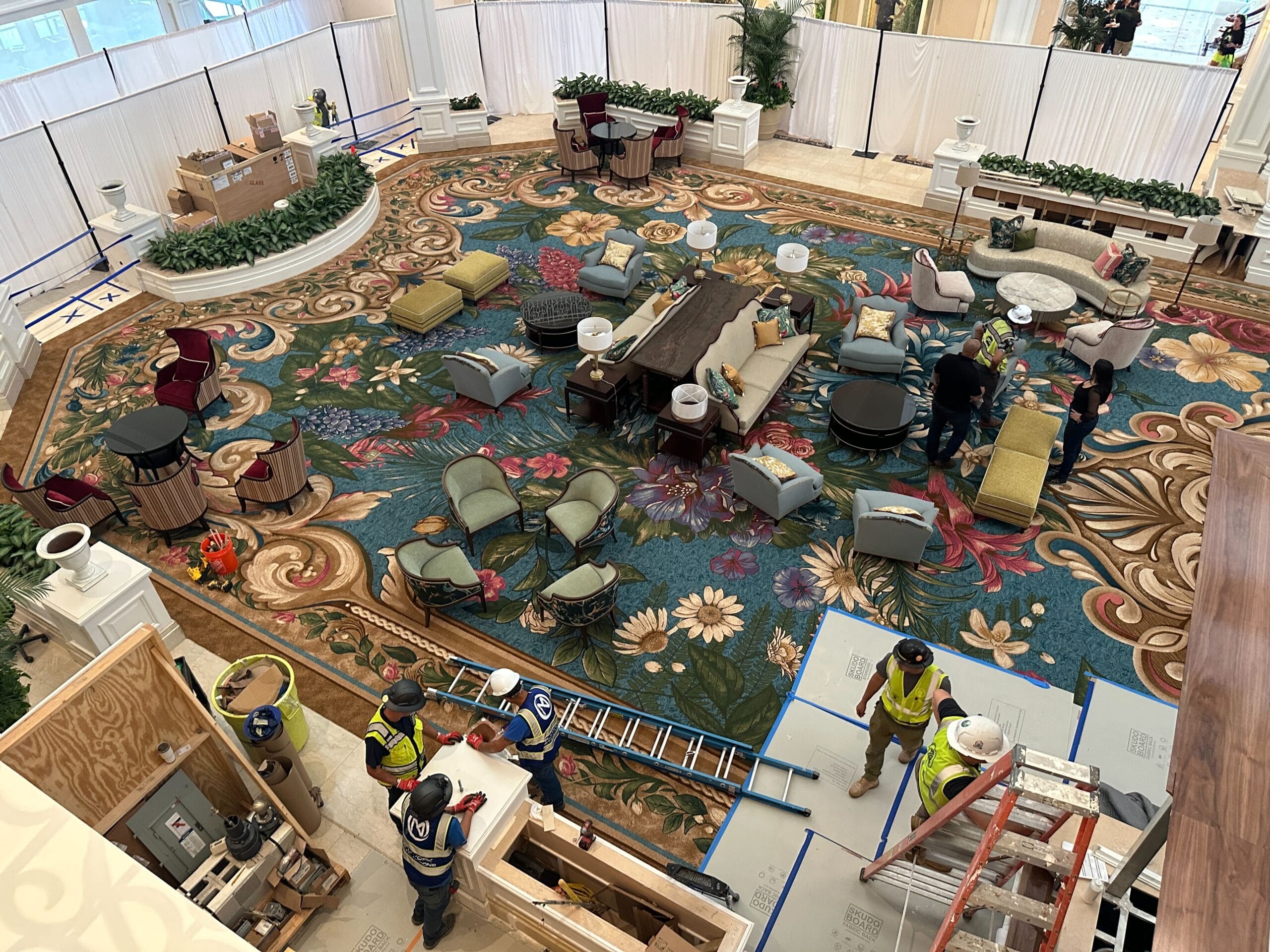 Cast members arrange elegant furniture in the Grand Floridian Resort lobby, its Victorian decor rivaling Disney castle grandeur.