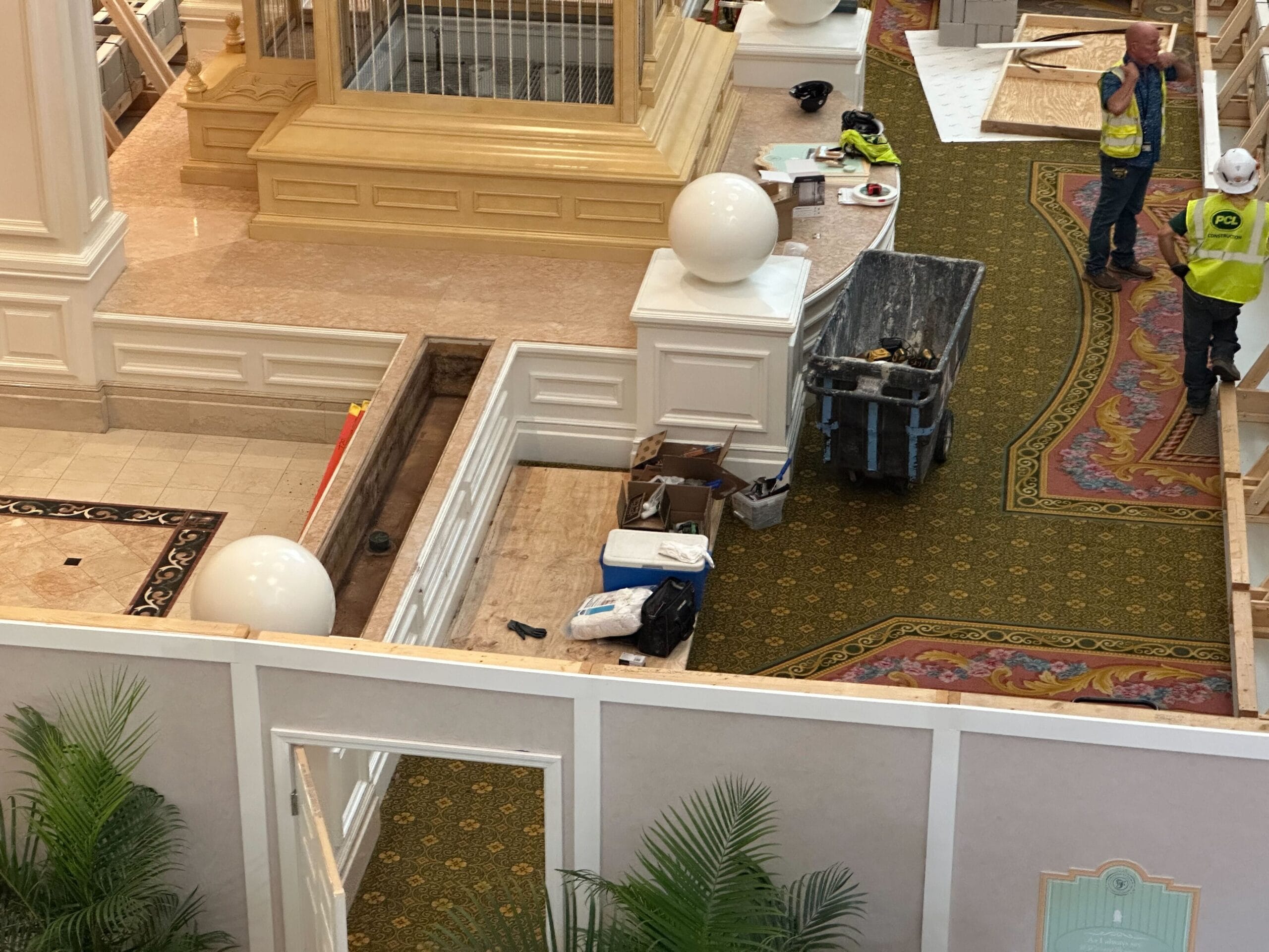 Indoor Lobby Construction at Grand Floridian with workers, tools, paint and signage near white railings and balls.