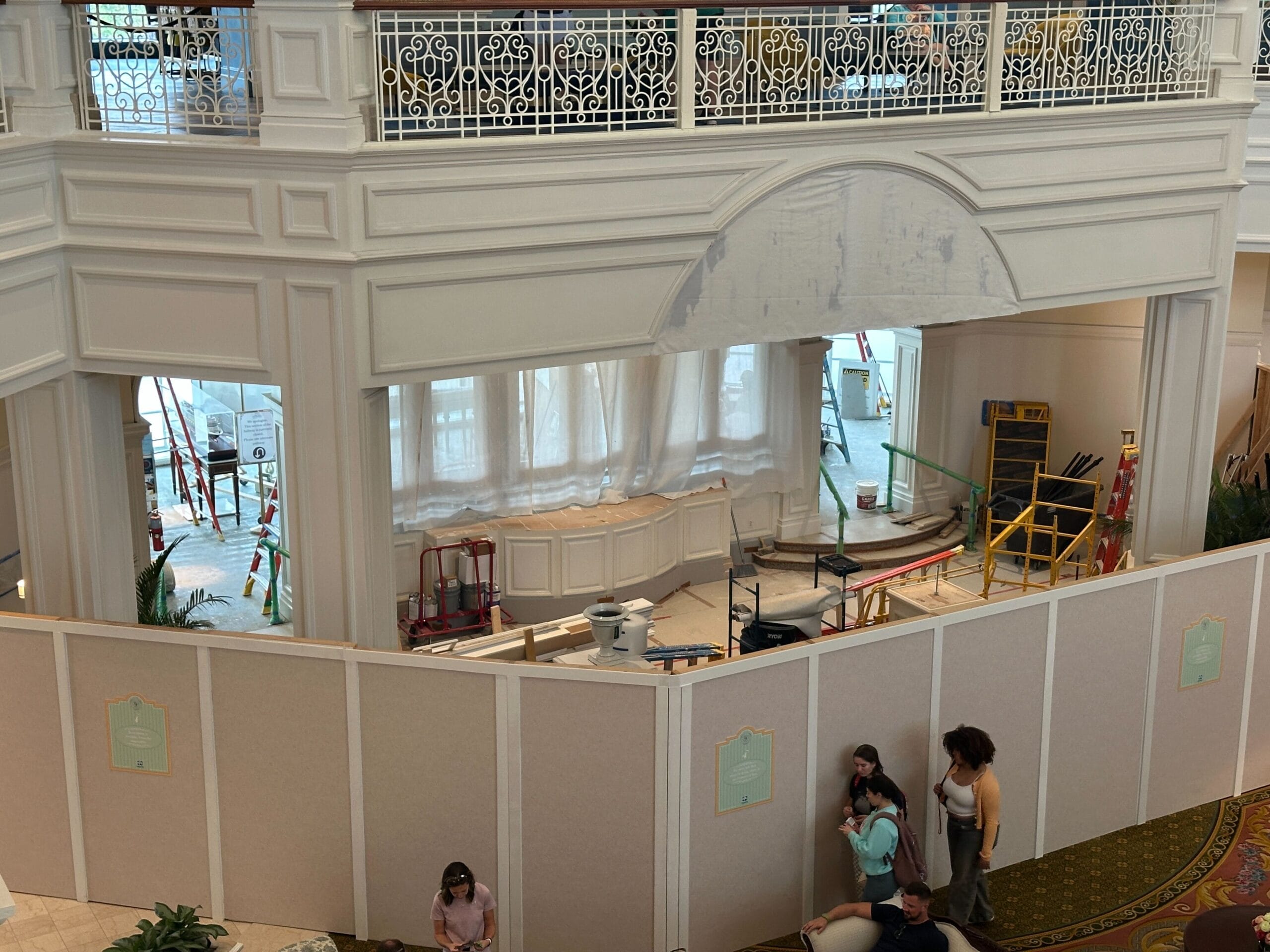 A hotel lobby under construction, with barriers and equipment, while people walk nearby.