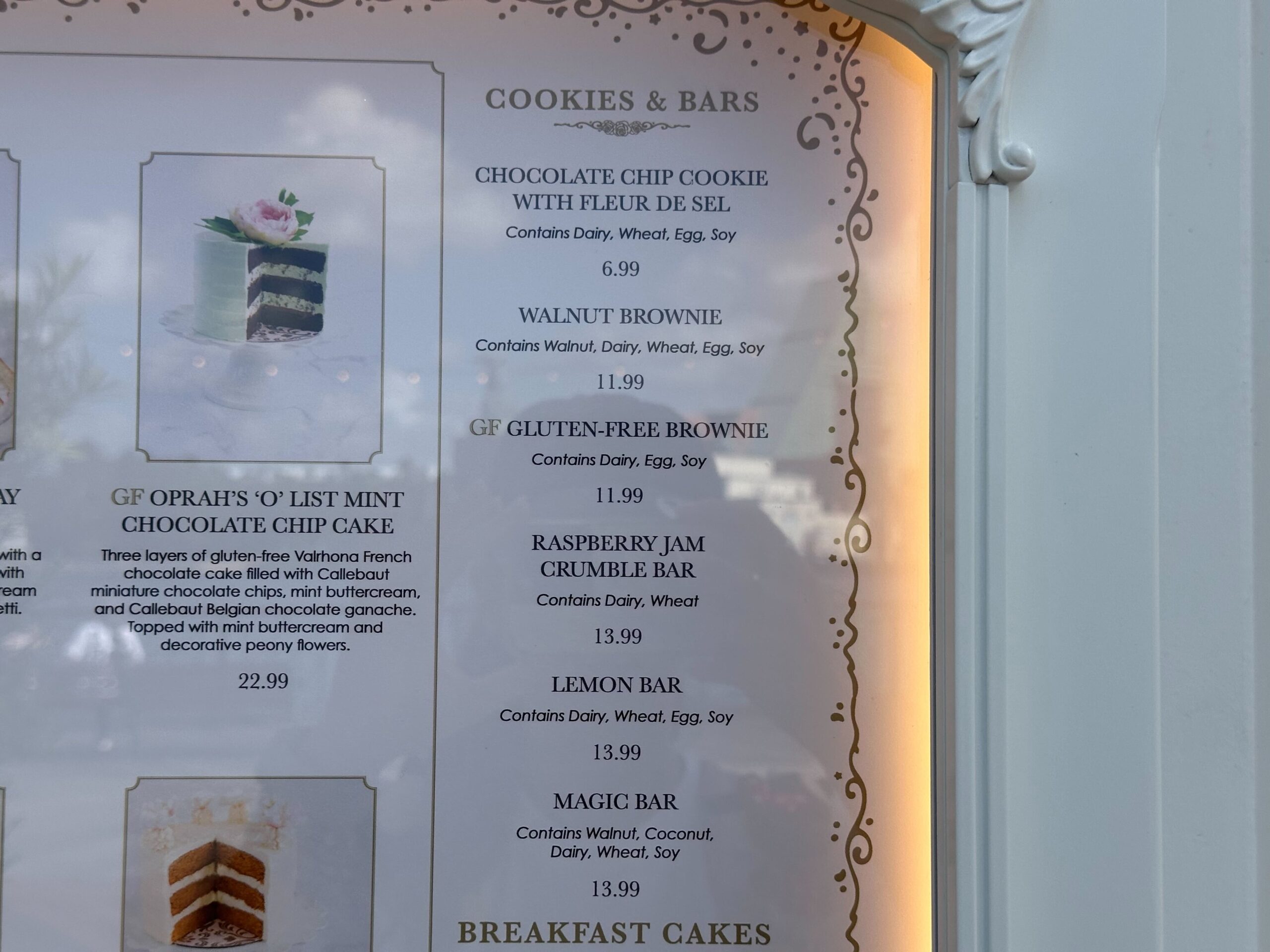 Explore the delightful menu at our Cake Bake Shop, featuring a tempting array of cookies and bars like chocolate chip cookie, walnut brownie, gluten-free brownie, raspberry jam crumble bar, lemon bar, and magic bar—all with prices to make your sweet tooth sing.