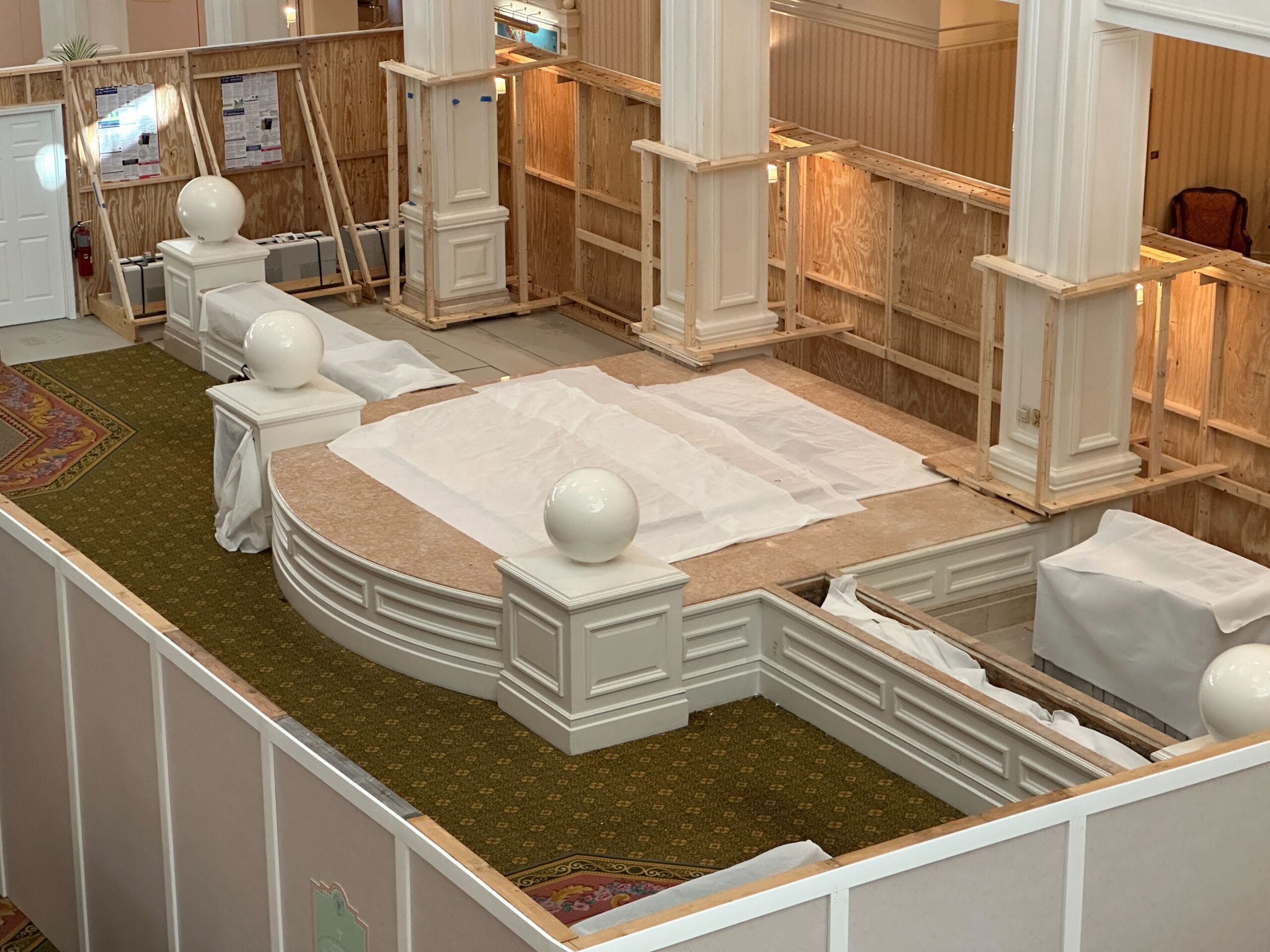 An indoor area under renovation at Disney’s Grand Floridian Resort with covered furniture and green patterned carpet.