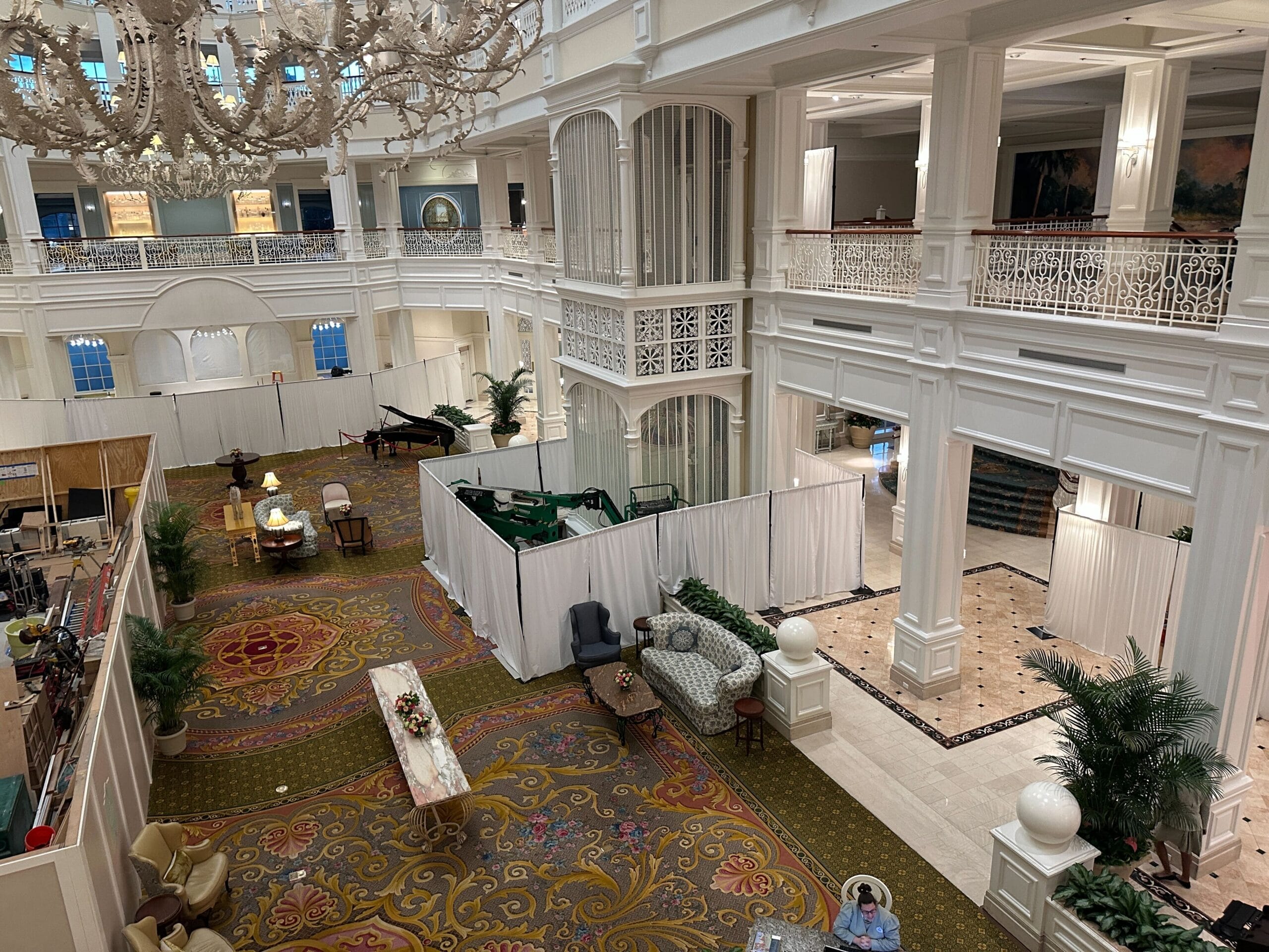 Hotel lobby with elegant décor, large chandelier, and white construction curtains sectioning off part of the space.