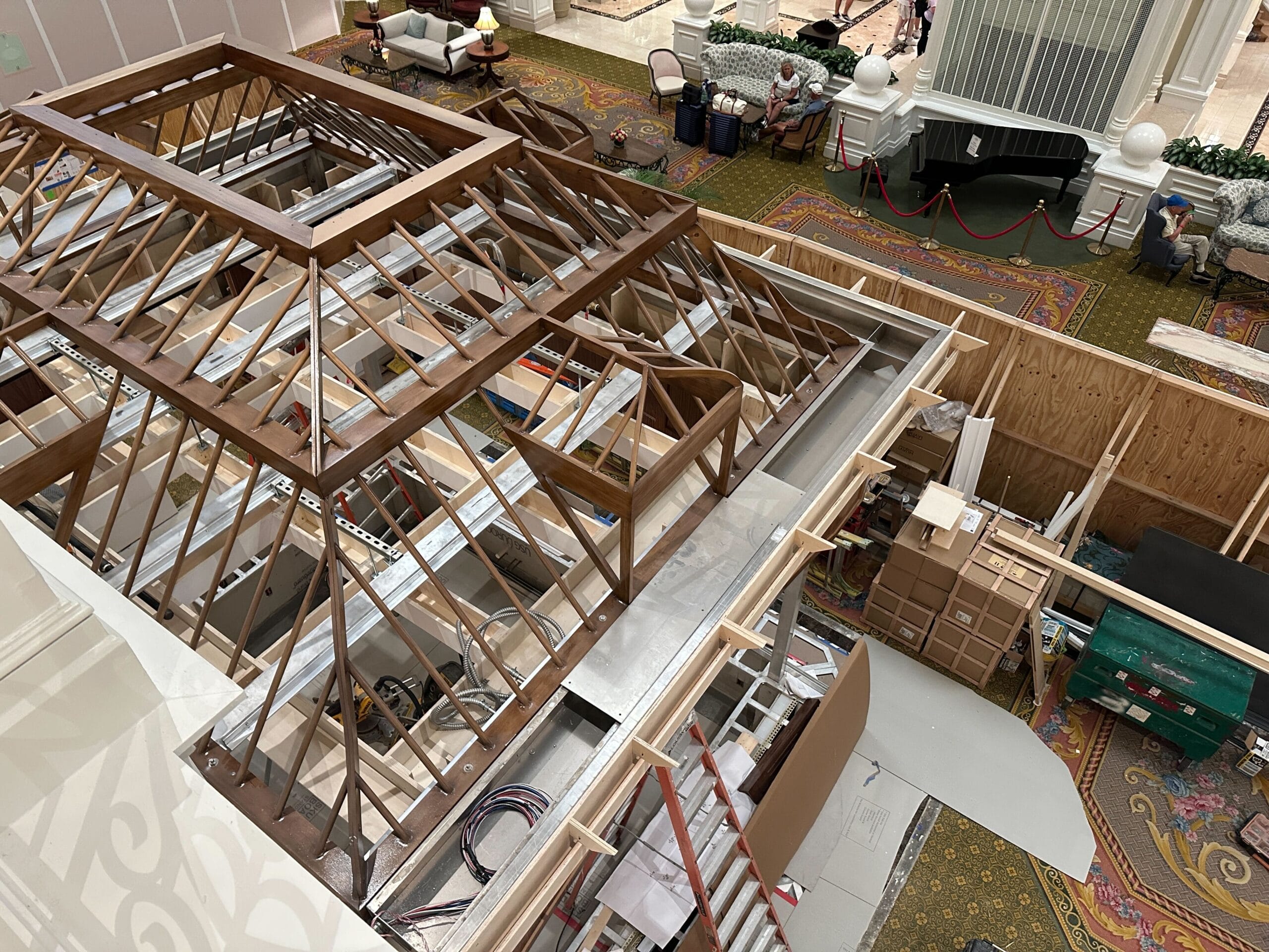 Overhead view of an indoor Grand Floridian construction area with wooden framework, tools, boxes, and building materials.
