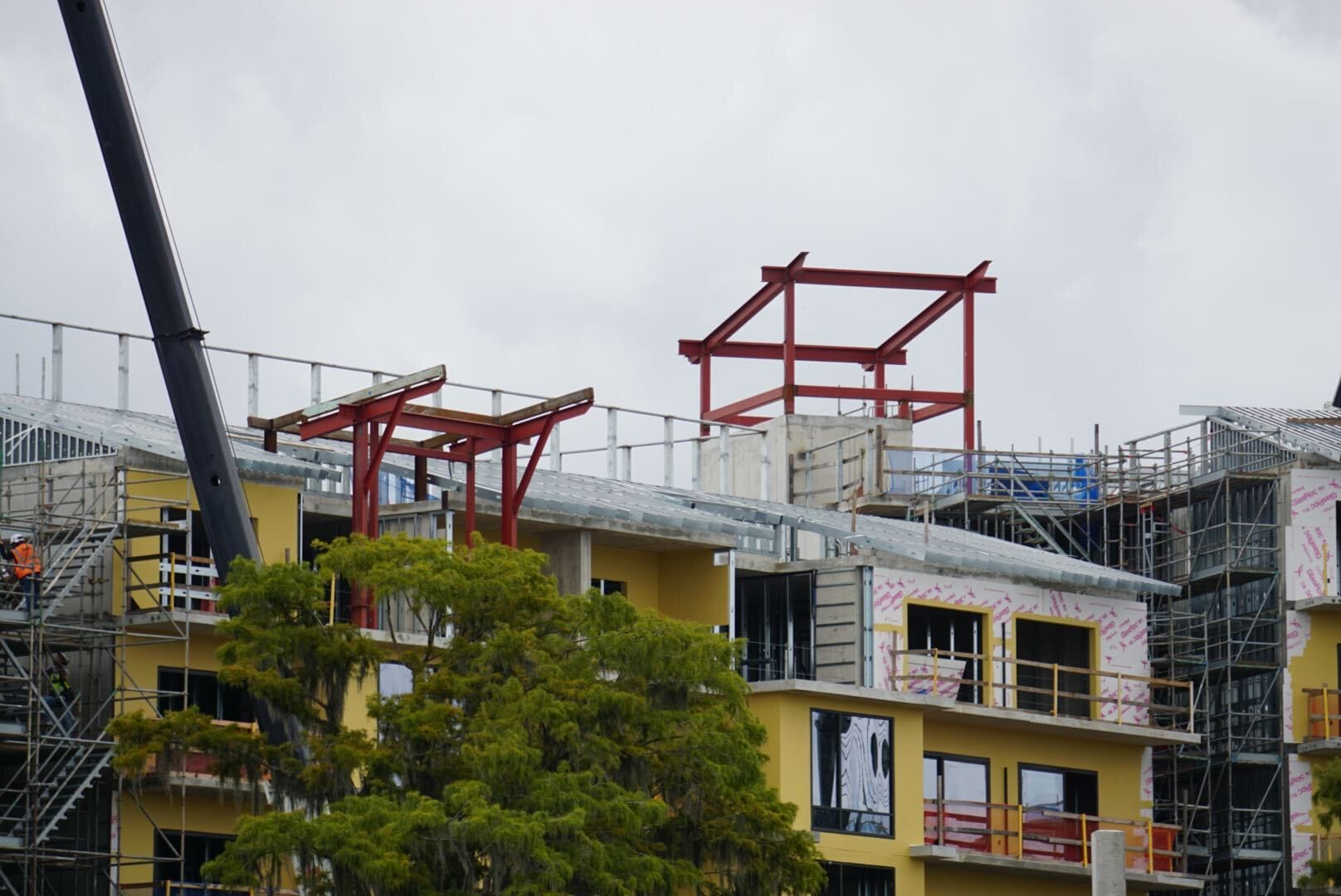 A building under construction on Lakeshore, with scaffolding, steel beams, and a crane against a cloudy sky.
