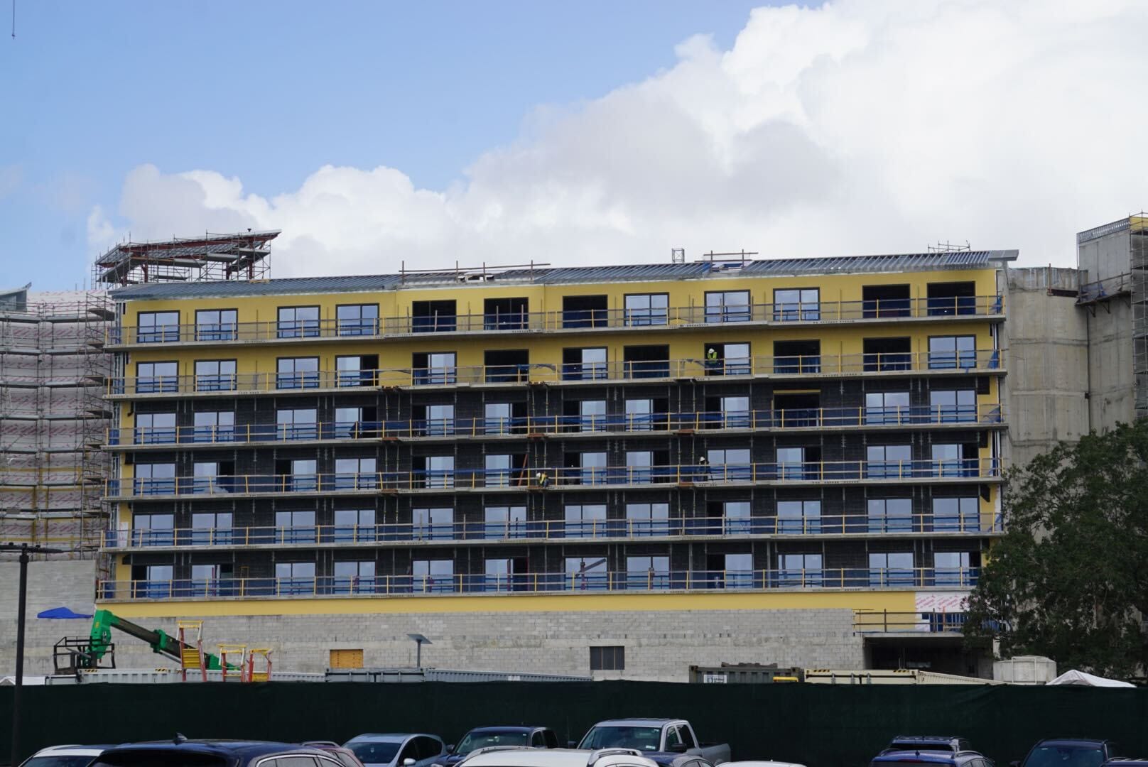 Lakeshore Lodge mid-rise under construction with scaffolding, yellow sheathing, and cars out front. Construction updates coming soon.