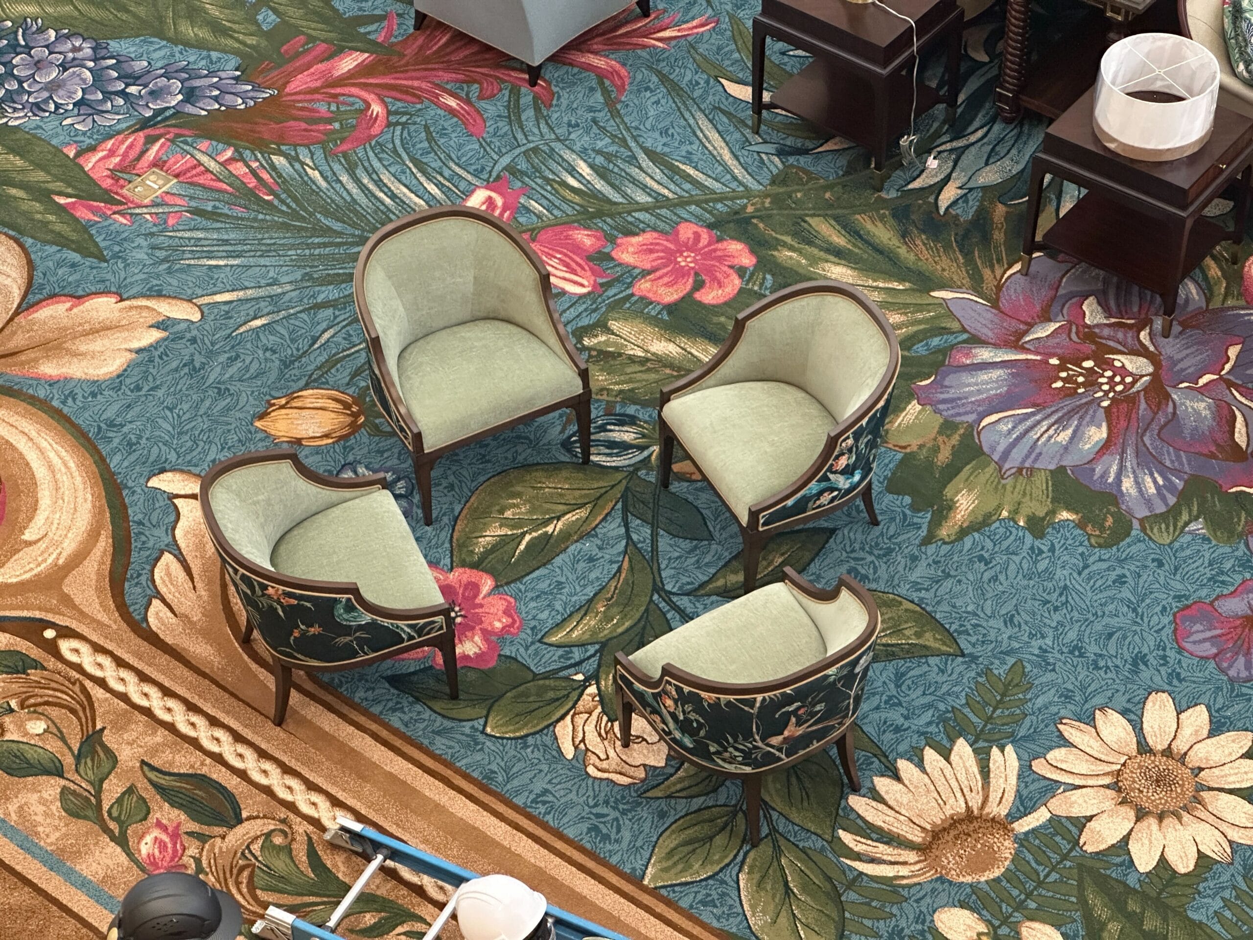 Four green armchairs form a circle on colorful carpet in Disney's Grand Floridian, evoking classic Disney resort elegance.