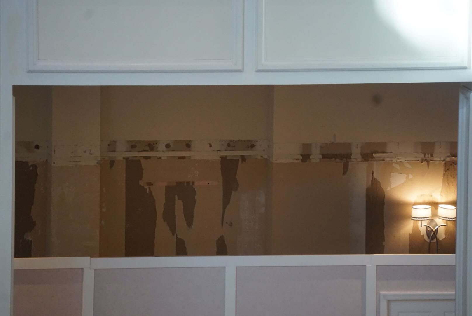 A partially stripped wall with exposed plaster and a lit wall sconce evokes H2O Glow After Hours vibes.