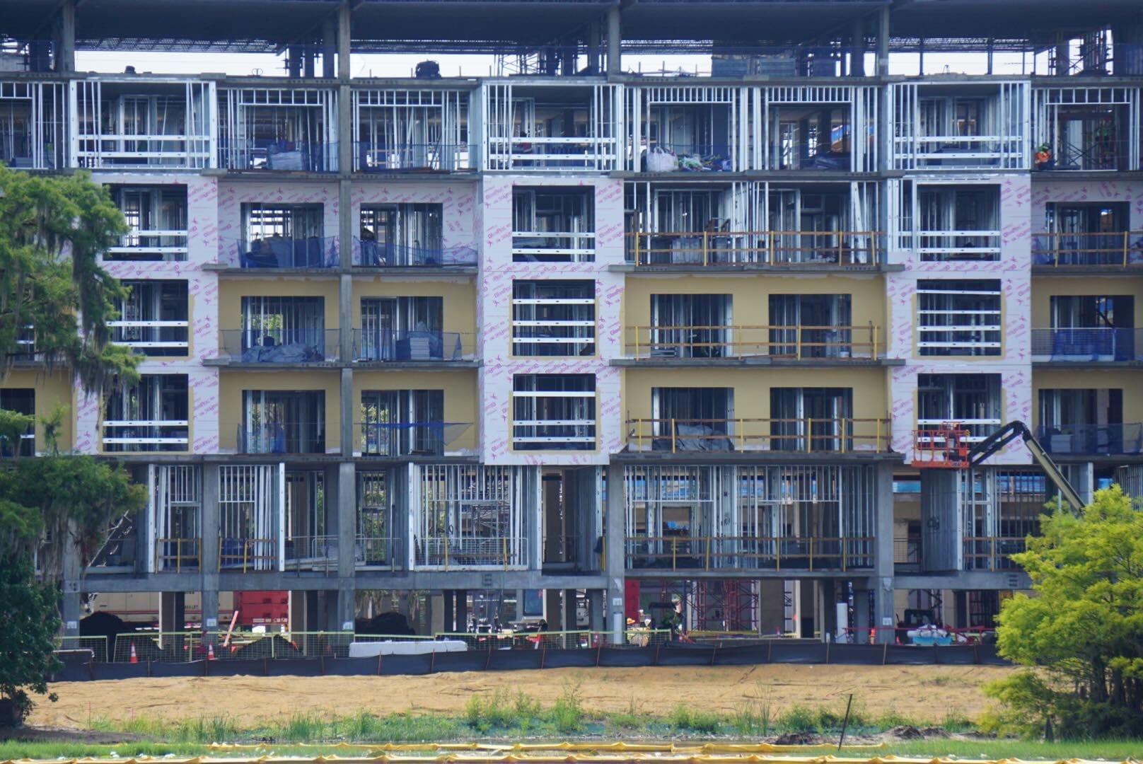 A multi-story building under construction with exposed frames, balconies, and construction materials visible.