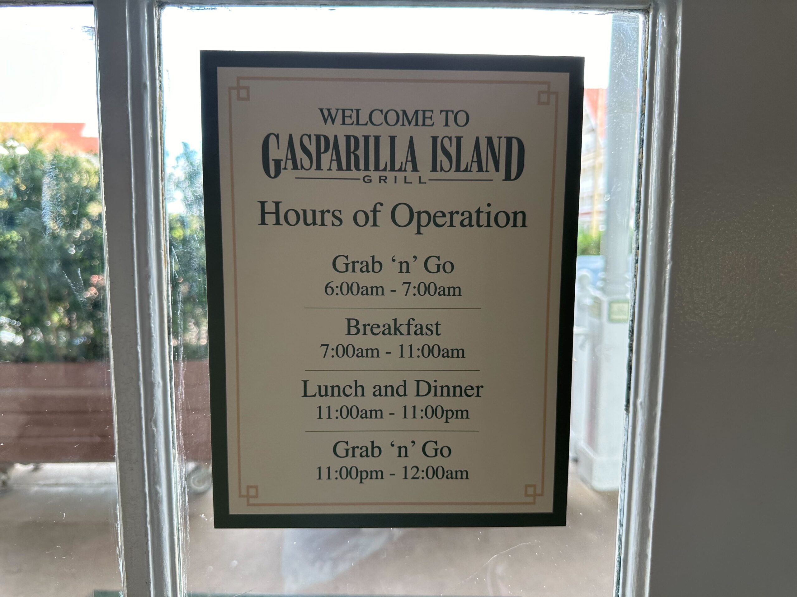 Sign displaying hours of operation for Gasparilla Island Grill, including Grab 'n' Go, breakfast, lunch, dinner, and late-night Grab 'n' Go options, from 6:00 am to 12:00 am.