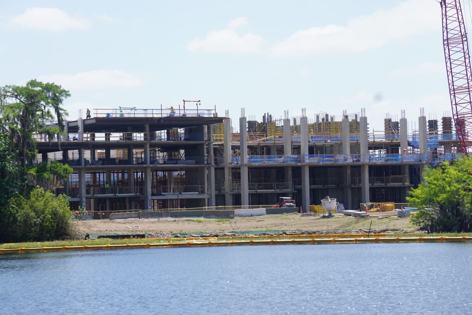 A multi-story building under construction near a body of water, with scaffolding and cranes visible.