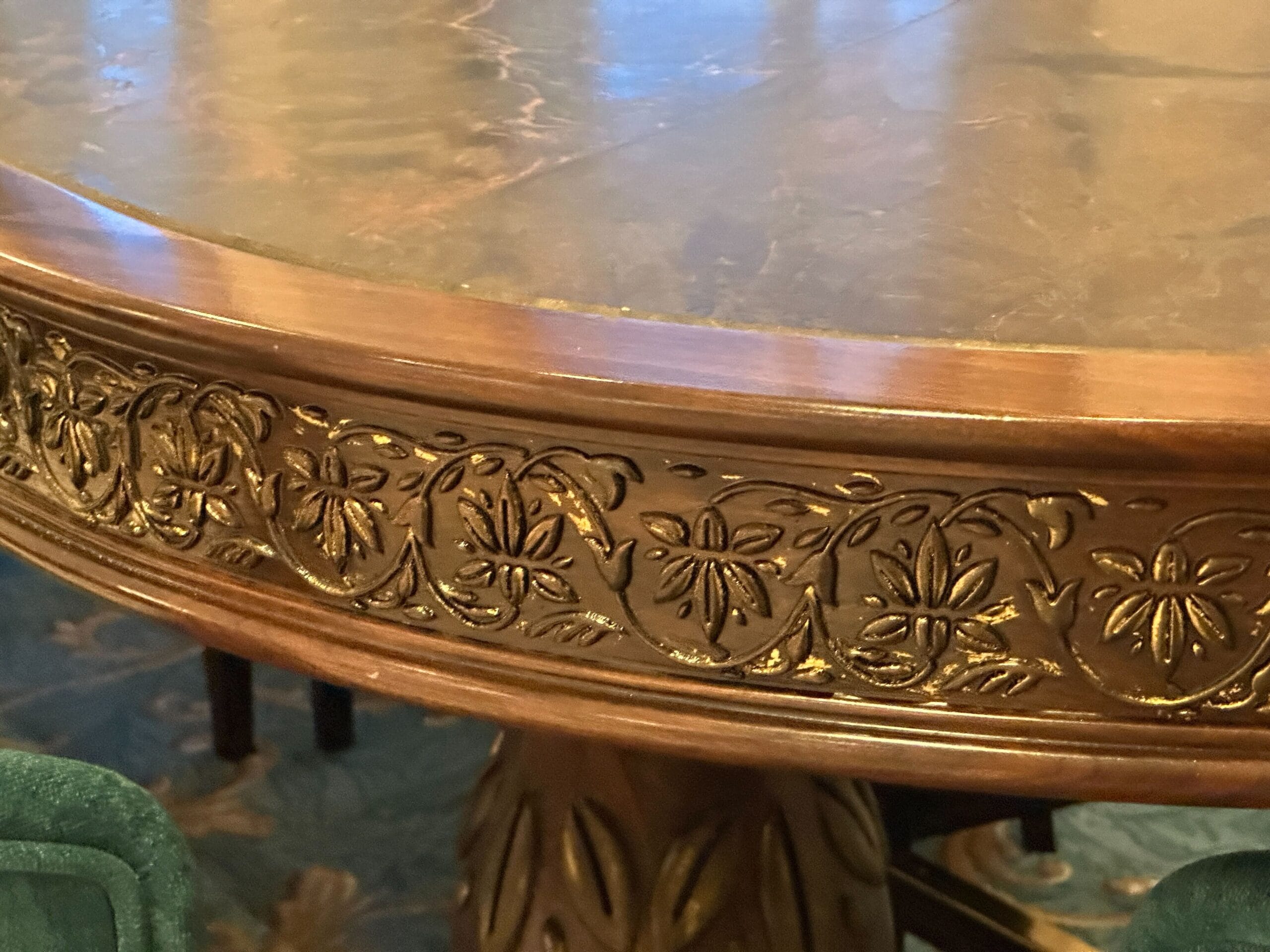 A close-up of a Grand Floridian wooden table edge with ornate floral carvings and gold accents.