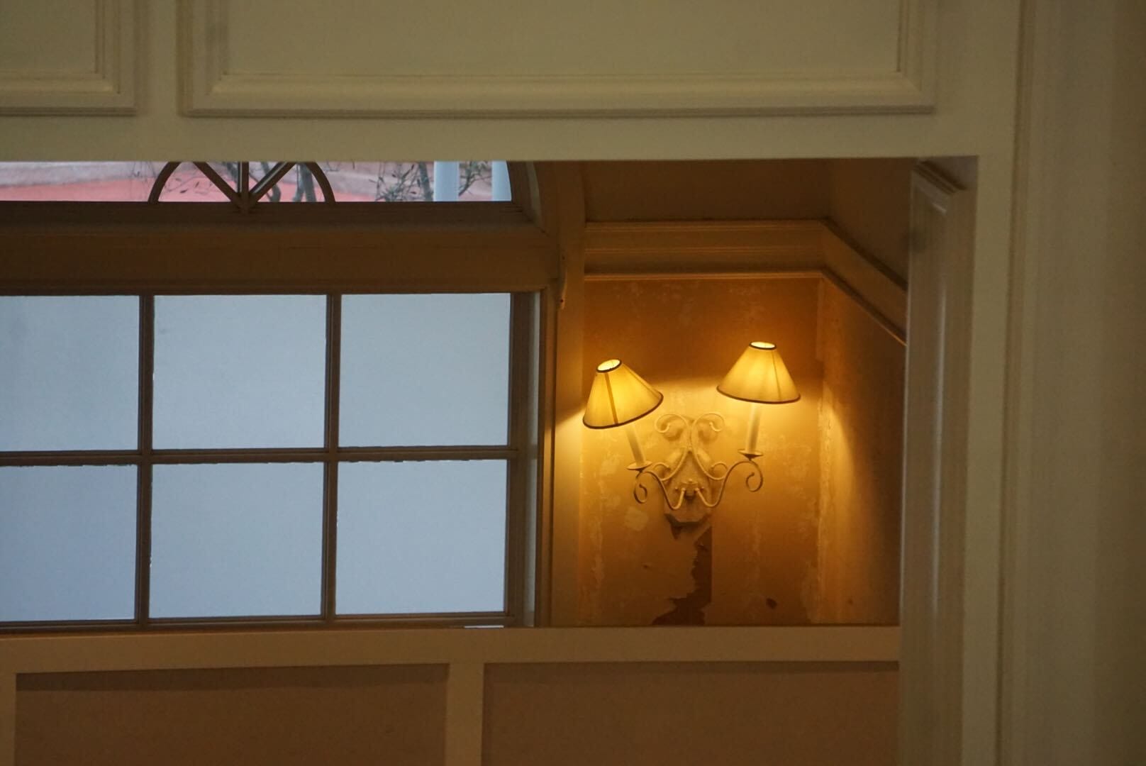 Two yellow wall lamps light up a cozy corner, perfect for enjoying H2O Glow After Hours food near frosted window panes.