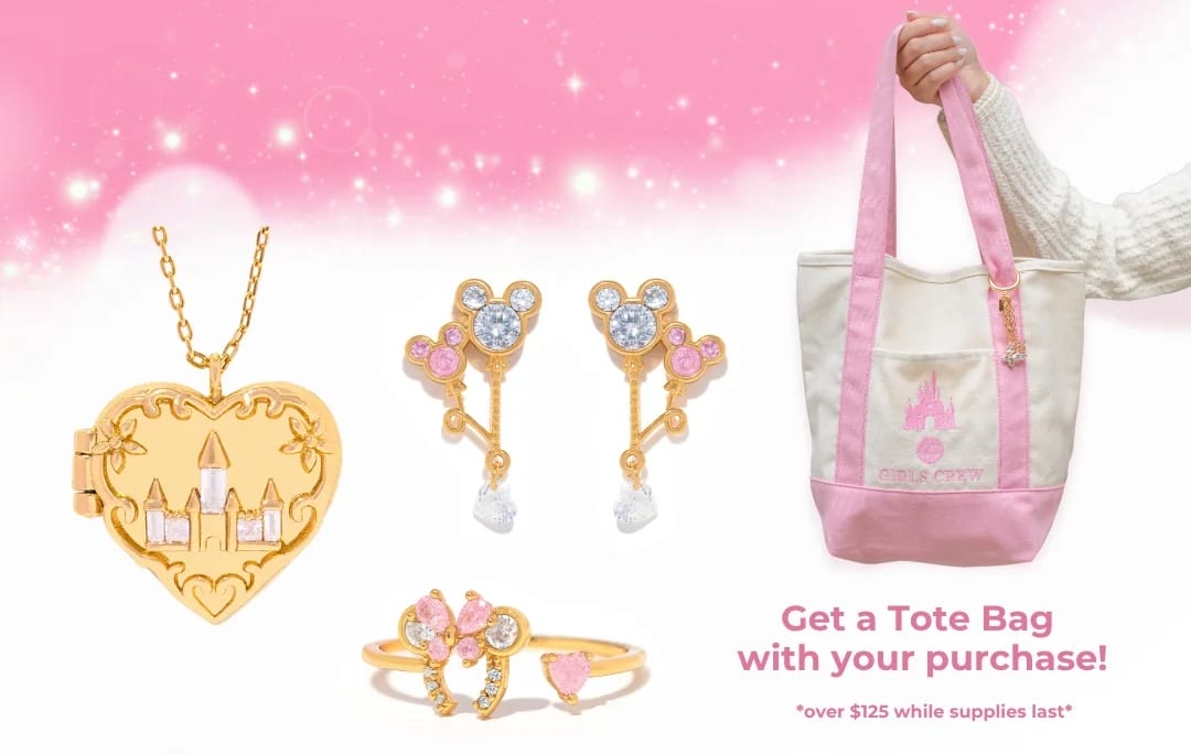 Gold Disney princess jewelry with pink and clear gems from the Disney Parks Collection, next to a pink-and-white tote bag.